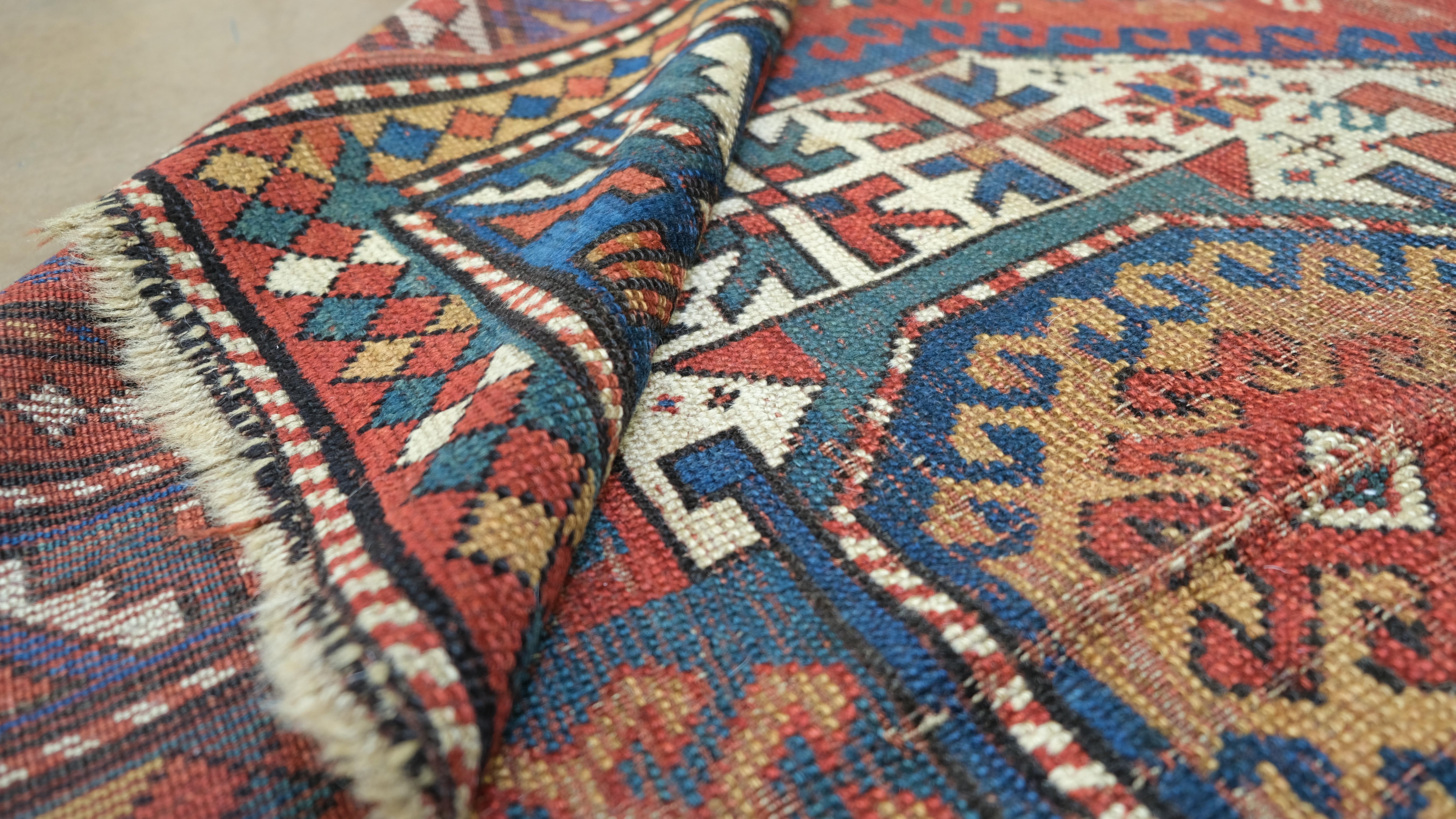 Infuse your space with the timeless charm of this hand-knotted Caucasian wool rug, showcasing a rich tapestry of traditional geometric patterns and medallion motifs. Woven in vivid hues of red, blue, and ivory, this rug exudes cultural heritage and