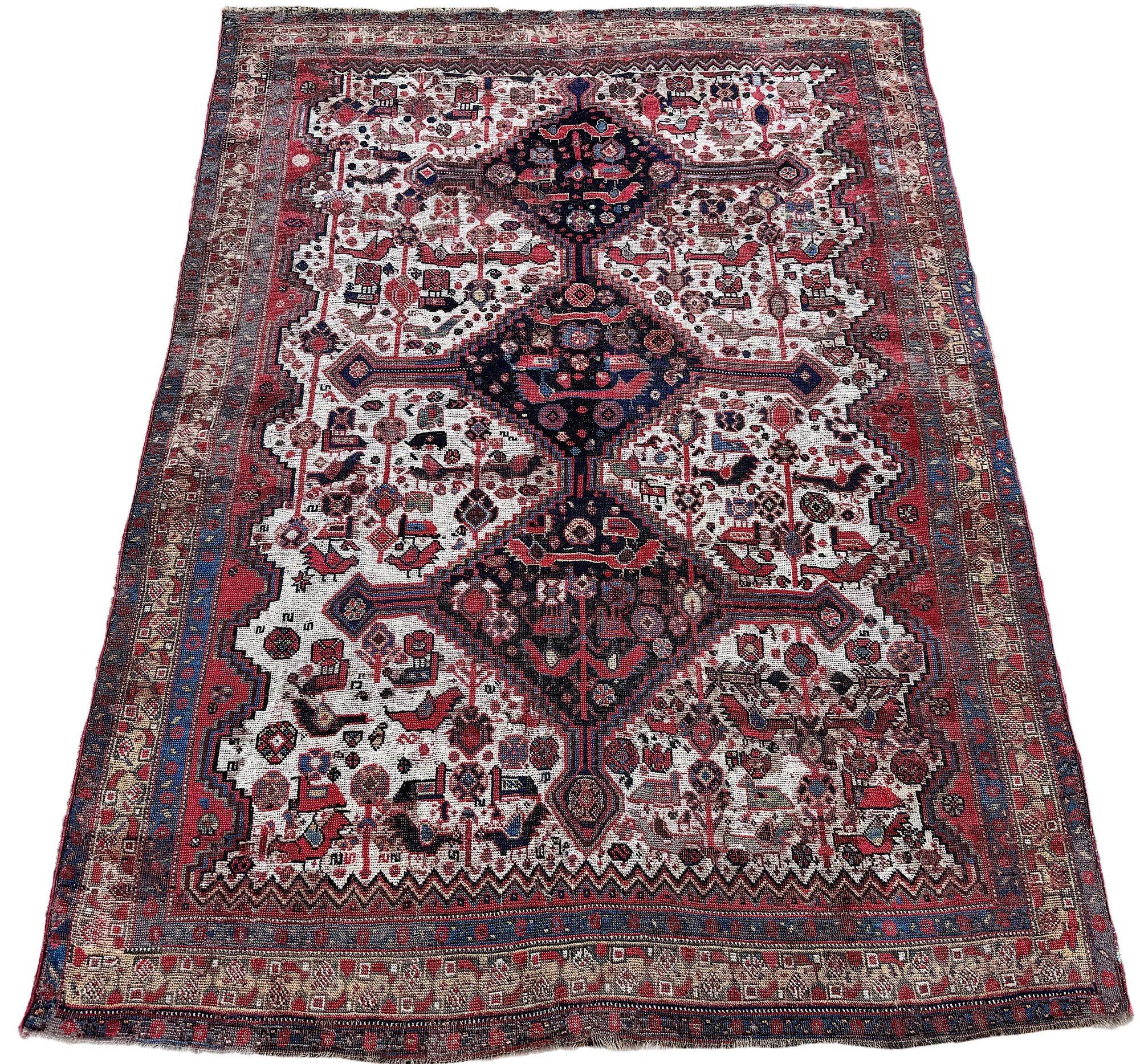 A beautiful antique tribal rug, woven by one of the nomadic tribes of the Khamseh confederation circa 1900. The design features 3 medallions on an unusual ivory field and camel border. Some heavy areas of wear which is reflected in the price but a
