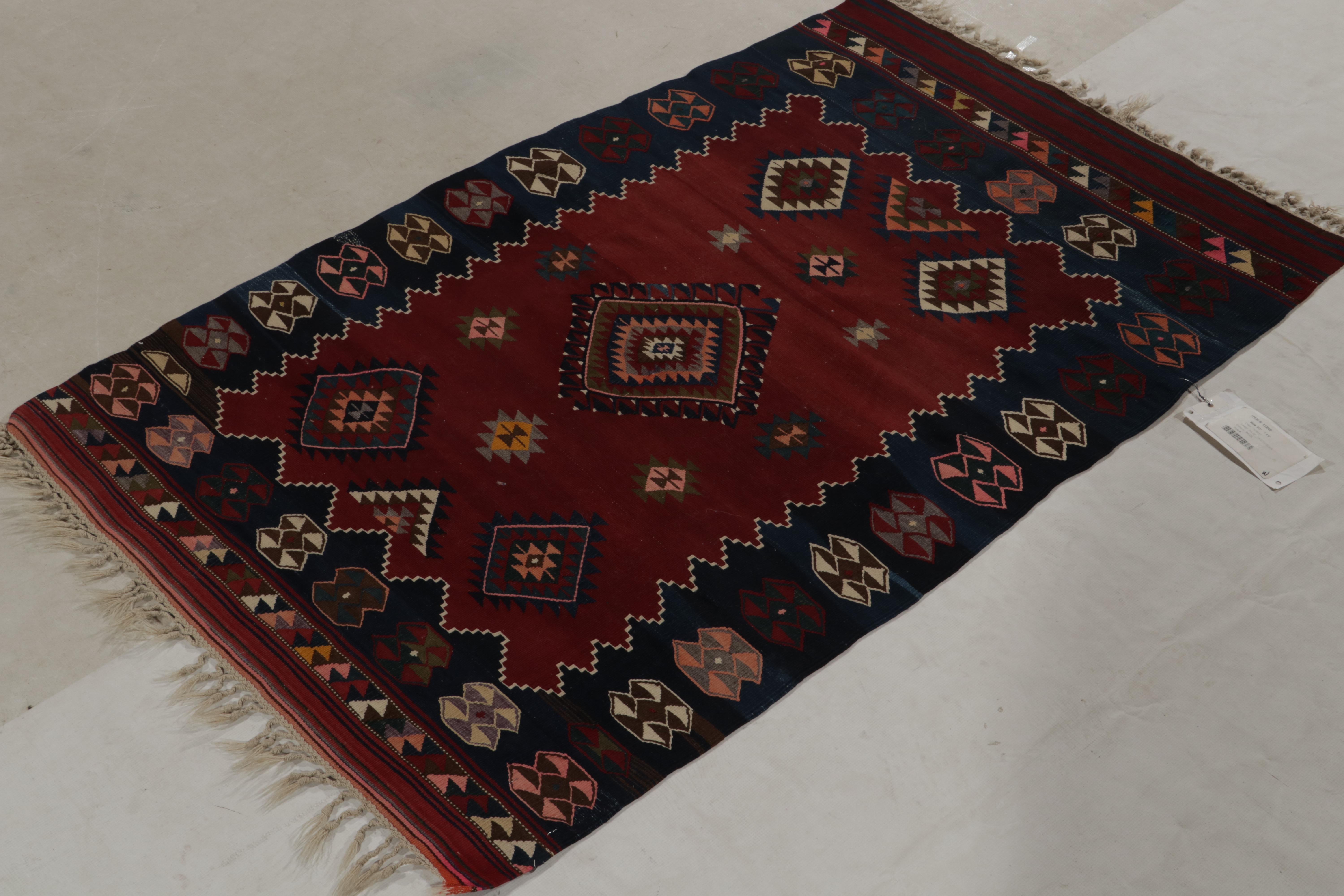Originaire de la région montagneuse de Yagcebeder en Turquie, ce tapis 3x5 est un kilim tribal ancien, datant des années 1930-1940. Tissé à la main en laine, le motif tribal est rouge avec un bord bleu profond, jouant avec le rose clair et d'autres