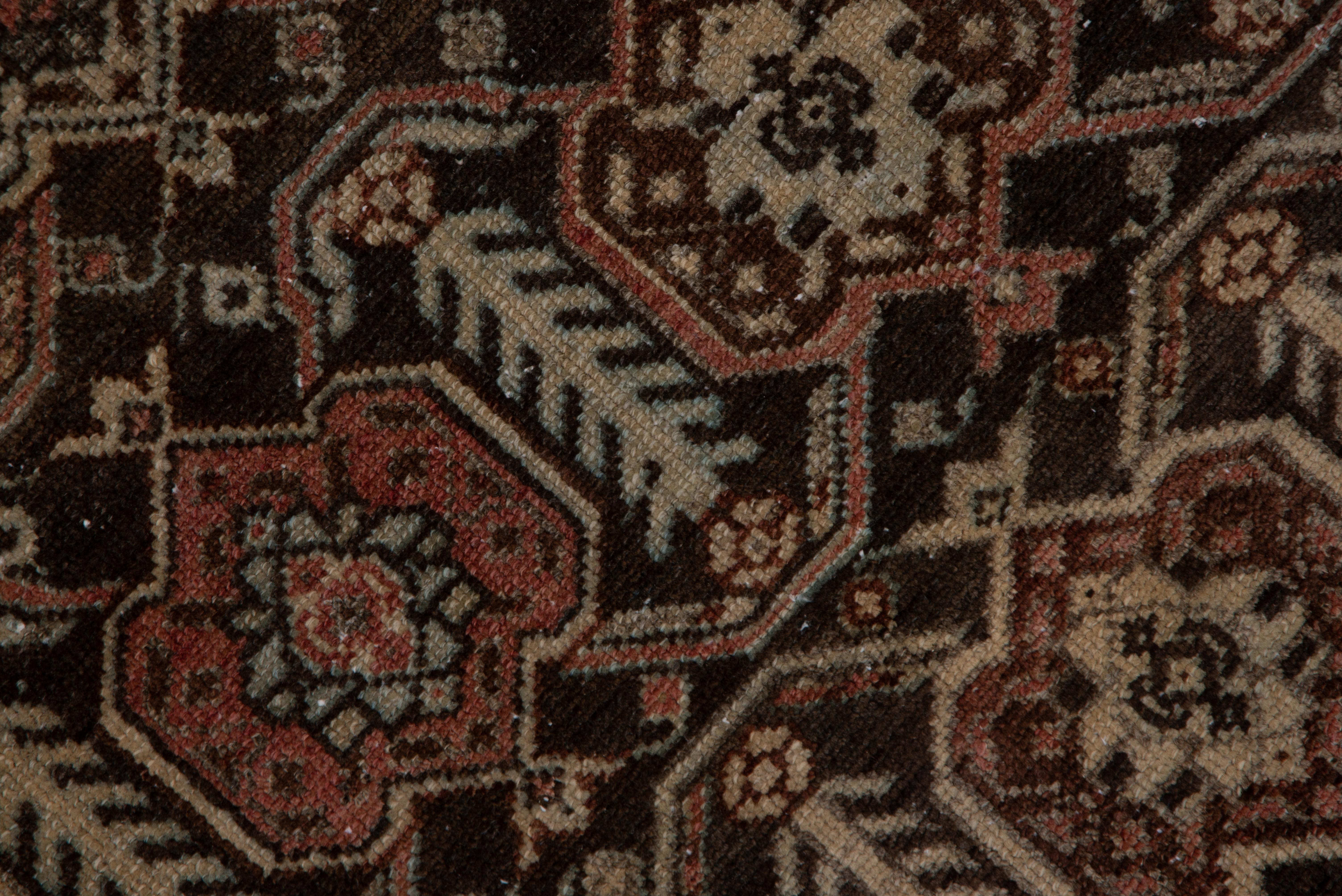 In a general Afshar style, with six offset rows of symmetric turtle palmettes on a chocolate brown ground. This west Persian rustic scatter continues the tribal aesthetic with a rose-brown border of petal palmettes and botehs.