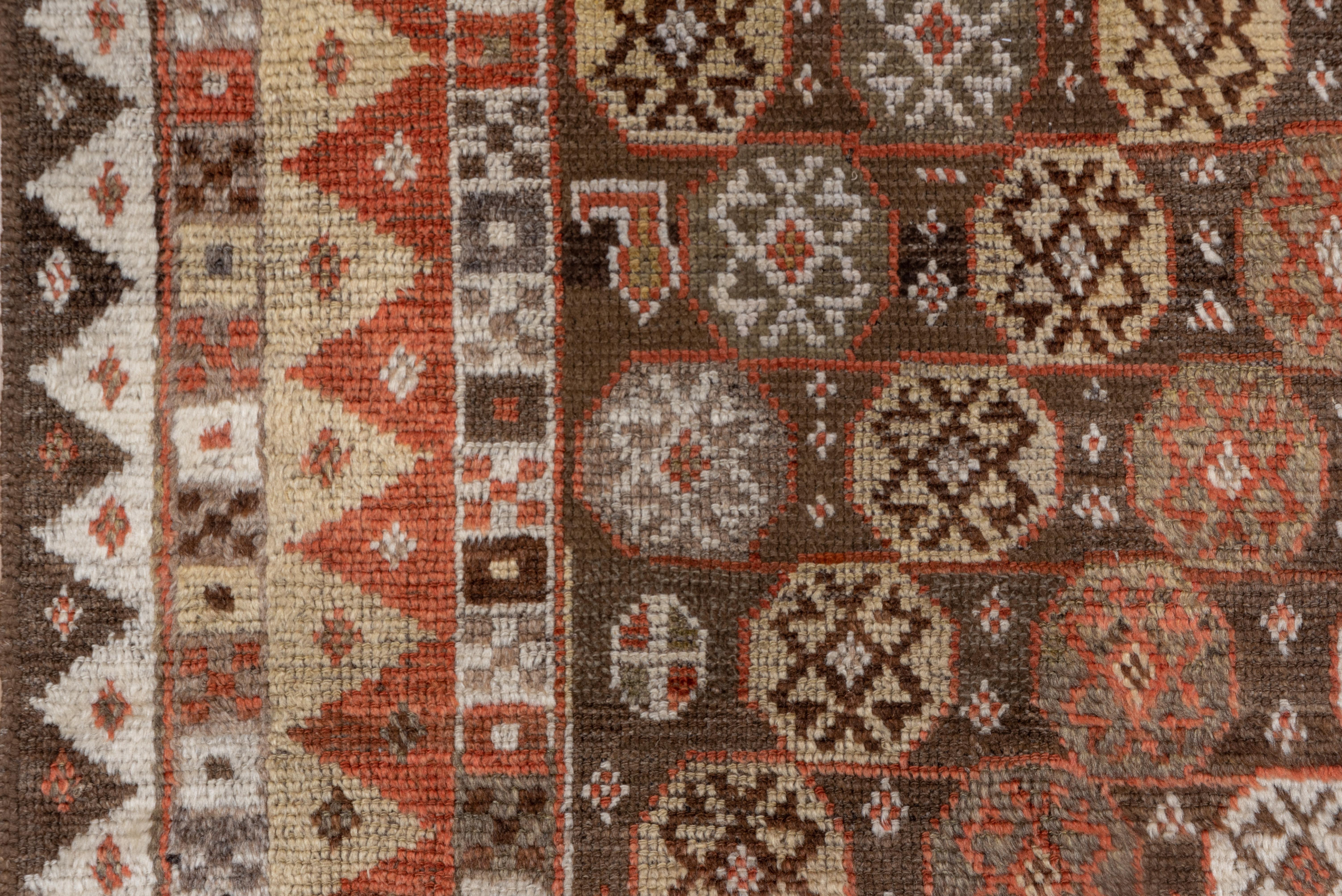 This southwest Persian nomadic scatter features a sienna field with diagonal rows of straw, sand, green and rose octagons enclosing multiply hooked lozenges, within bi tonal triangle borders.