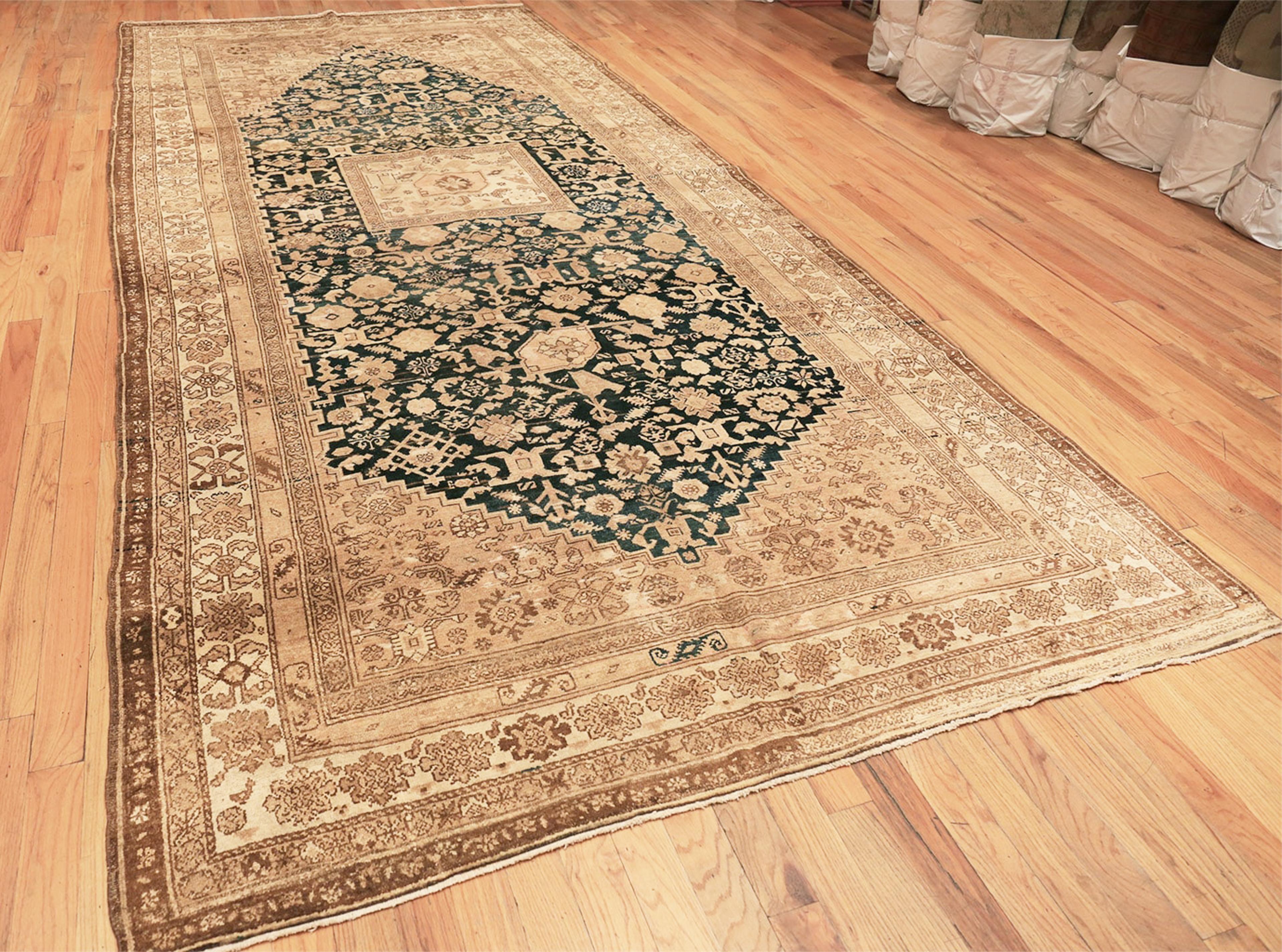 Tribal gallery size antique Persian Malayer rug, country of origin: Persia, date circa 1900. Size: 7 ft x 15 ft 7 in (2.13 m x 4.75 m).

This antique Persian rug is a long banner with an almost black central field that draws the eye. Created in the