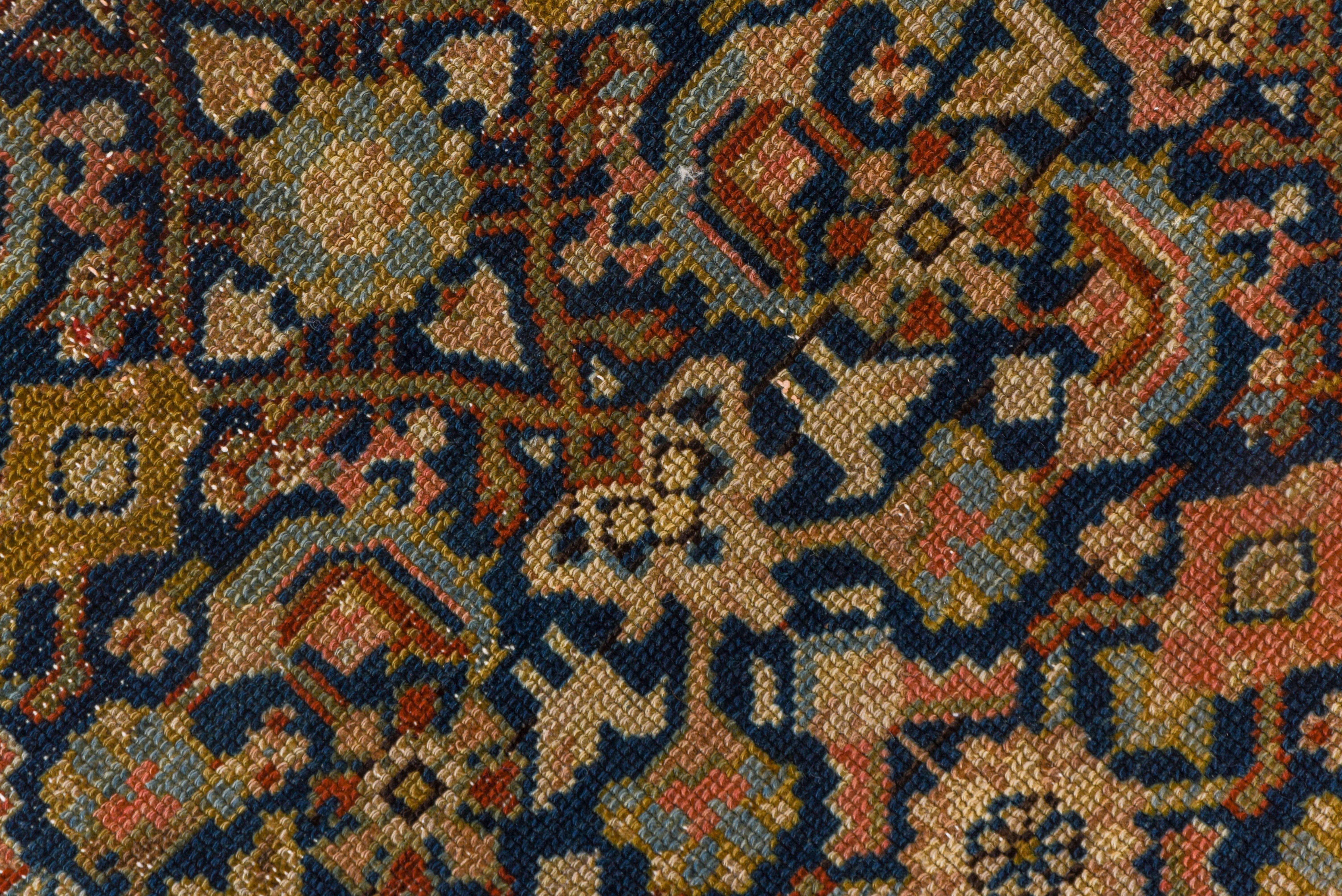 This west Persian long scatter ryg shows an allover Herati pattern detailed in rust and pale green, with numerous tiny birds. On a field abrashing from navy to chocolate. The main beige border shows palmettes and minute botehs on a tendril meander.
