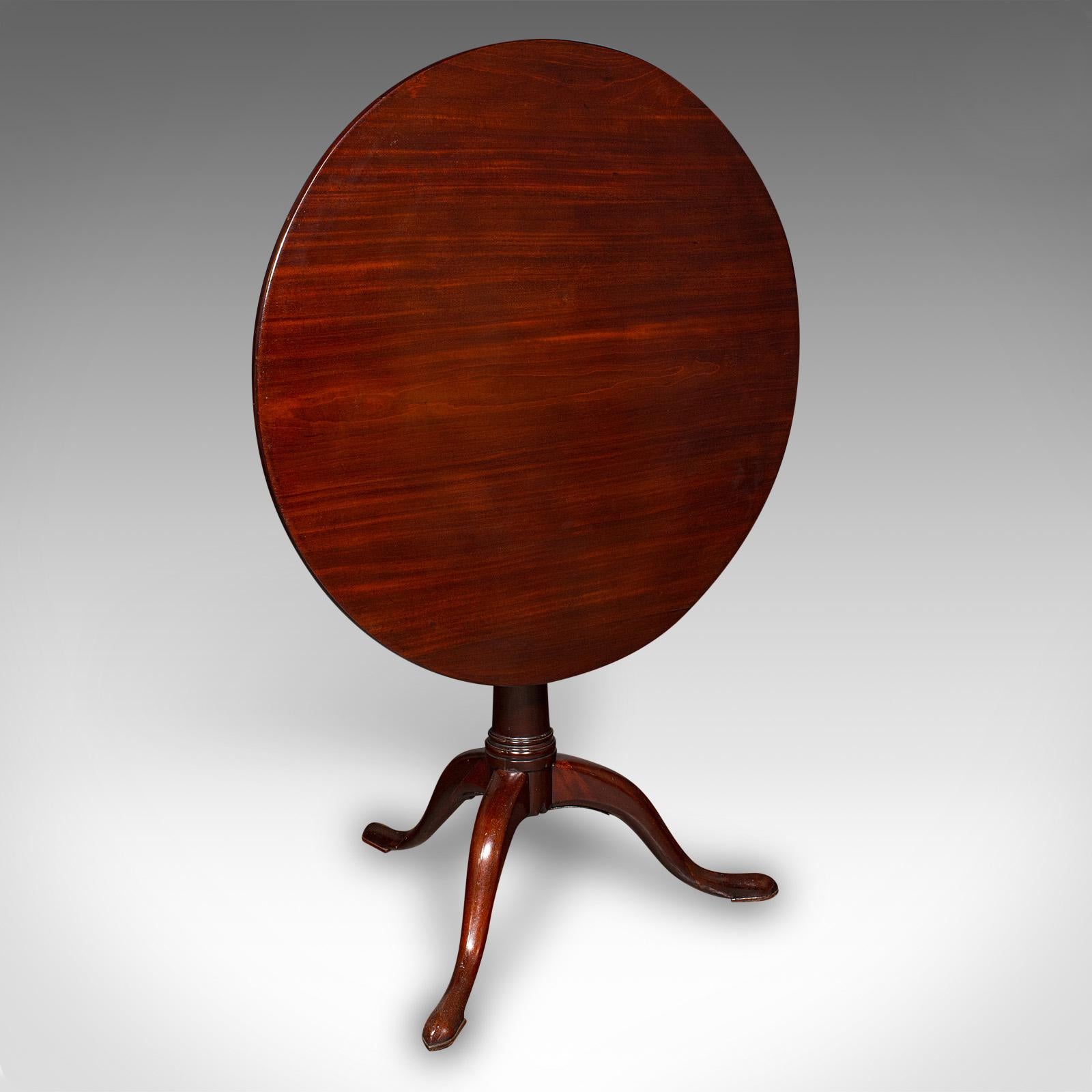 This is an antique tripod table. An English, mahogany tilt-top side table with birdcage mount, dating to the Georgian period, circa 1800. A superb example of Georgian craftsmanship, offering a tilting and rotating top for versatility and timeless