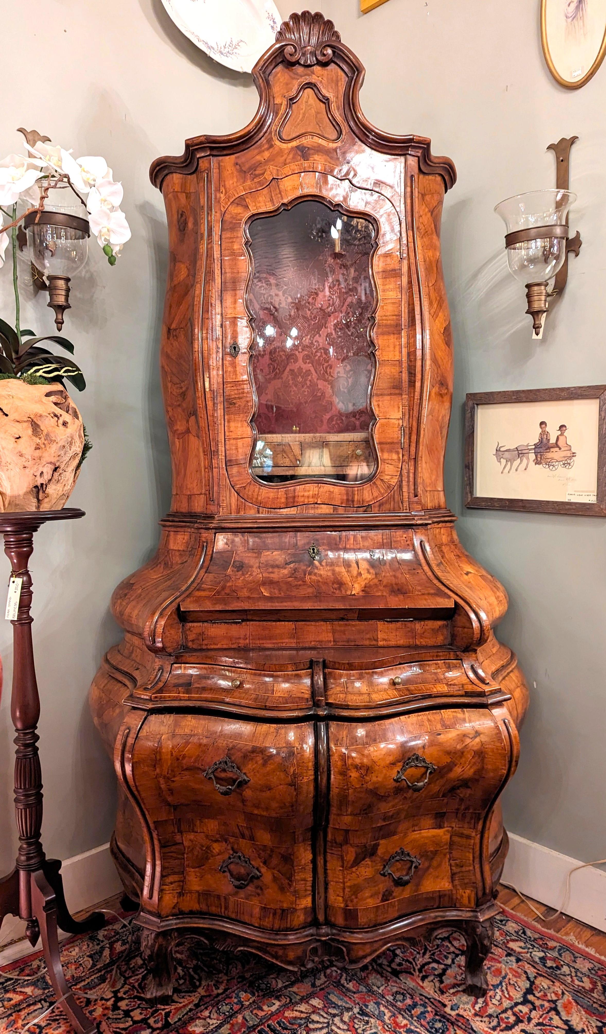 Attractive Italian Rococo style burl wood veneer secretary cabinet, circa early 20th century.
Double bodied with the top part of the cabinet over a slant-front desk with writing compartments. Stunning bombe form, several drawers adorned with bronze