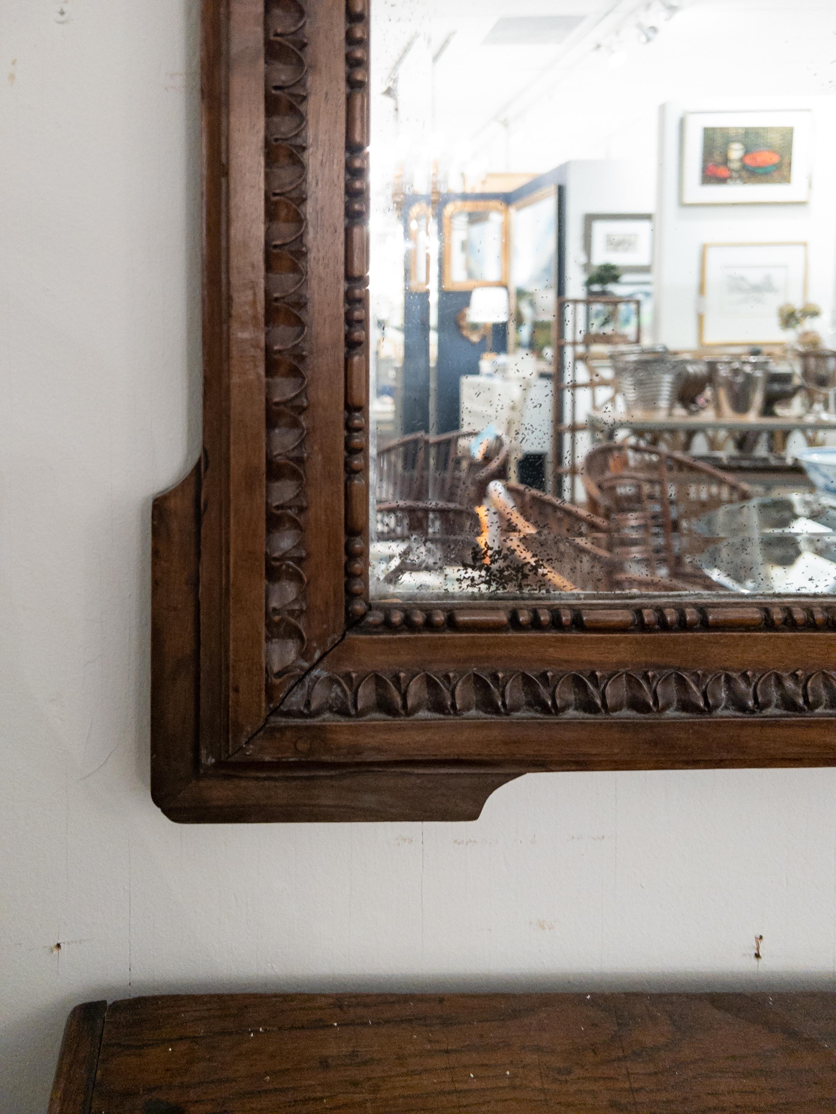 Miroir trumeau ancien sculpté avec panneau de tapisserie. L'ancien miroir biseauté est entouré de détails en forme d'œuf et de dard et le haut du panneau de tapisserie est orné d'une guirlande florale.