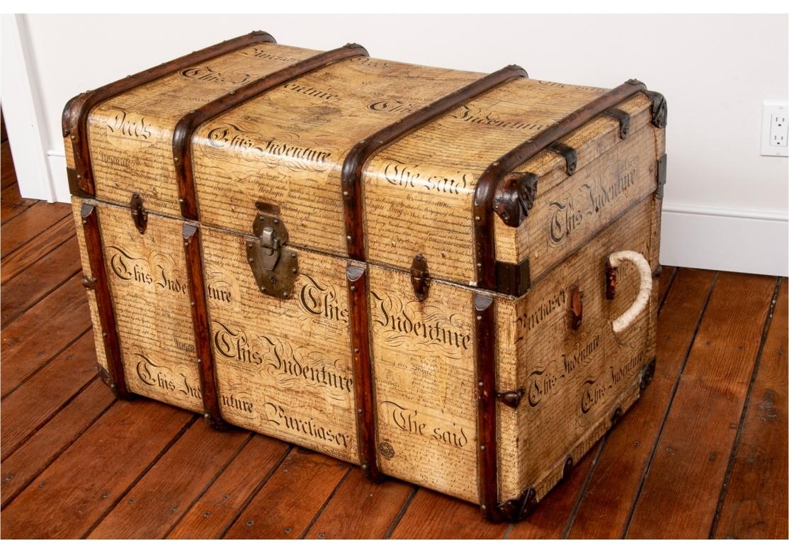 A large and decorative wood ribbed steamer trunk which has been refashioned using contemporary facsimile of Antique print titled, “This Indenture”. The color and treatment presents as a master blend between a true antique and a contemporary artist