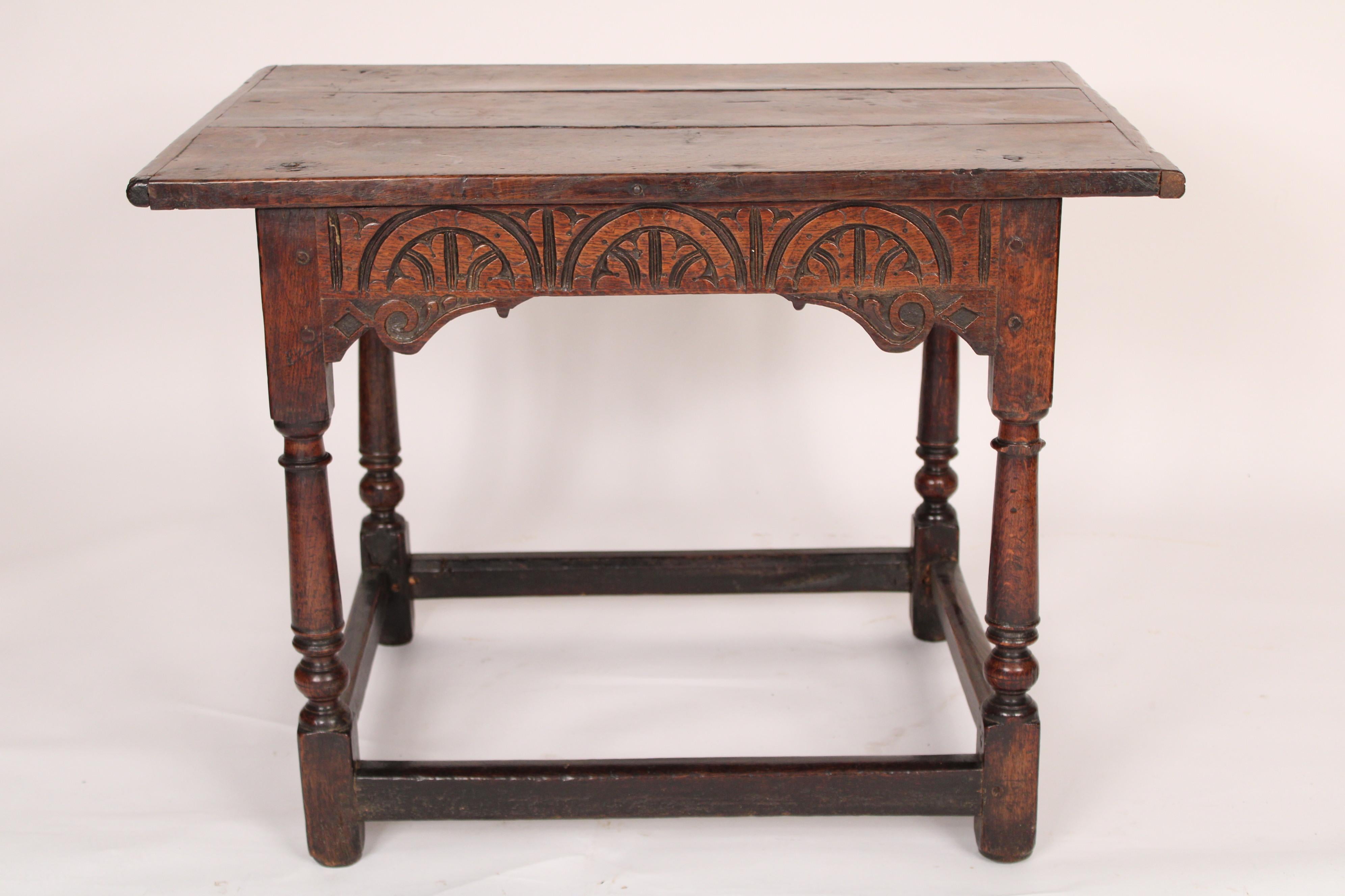 Antique Tudor style oak occasional table, 19th century. With a rectangular over hanging 3 board top, arched and carved decorations on the front and back frieze, turned legs joined by box stretchers. The oak has a nice old patina. Mortise tenon and
