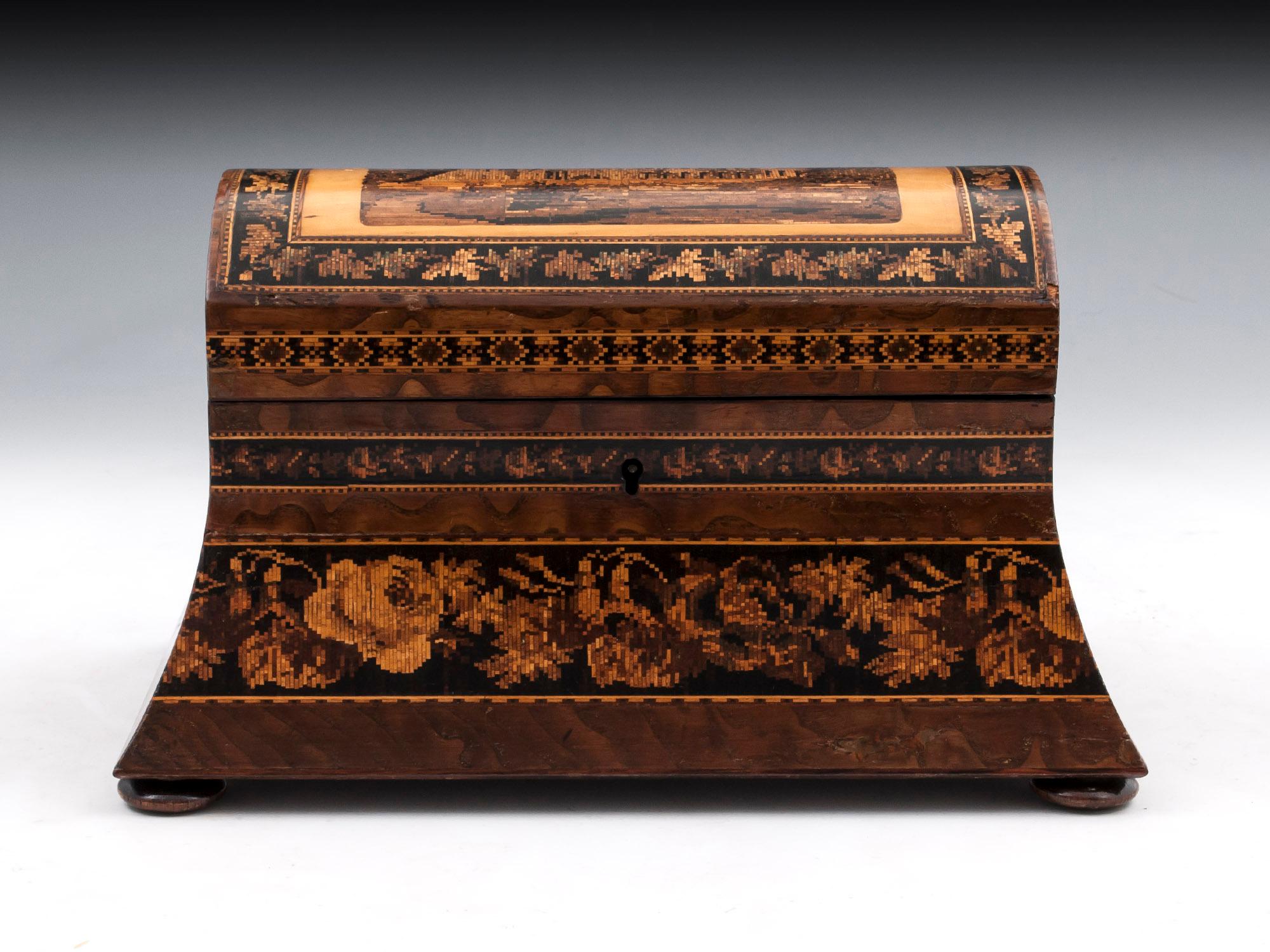 Tunbridge ware dome top tea caddy veneered in Hungarian ash with a view of Tonbridge Castle on the top, standing on four turned wooden feet. 

The Tunbridge ware tea caddy interior has two lidded compartments with turned wooden