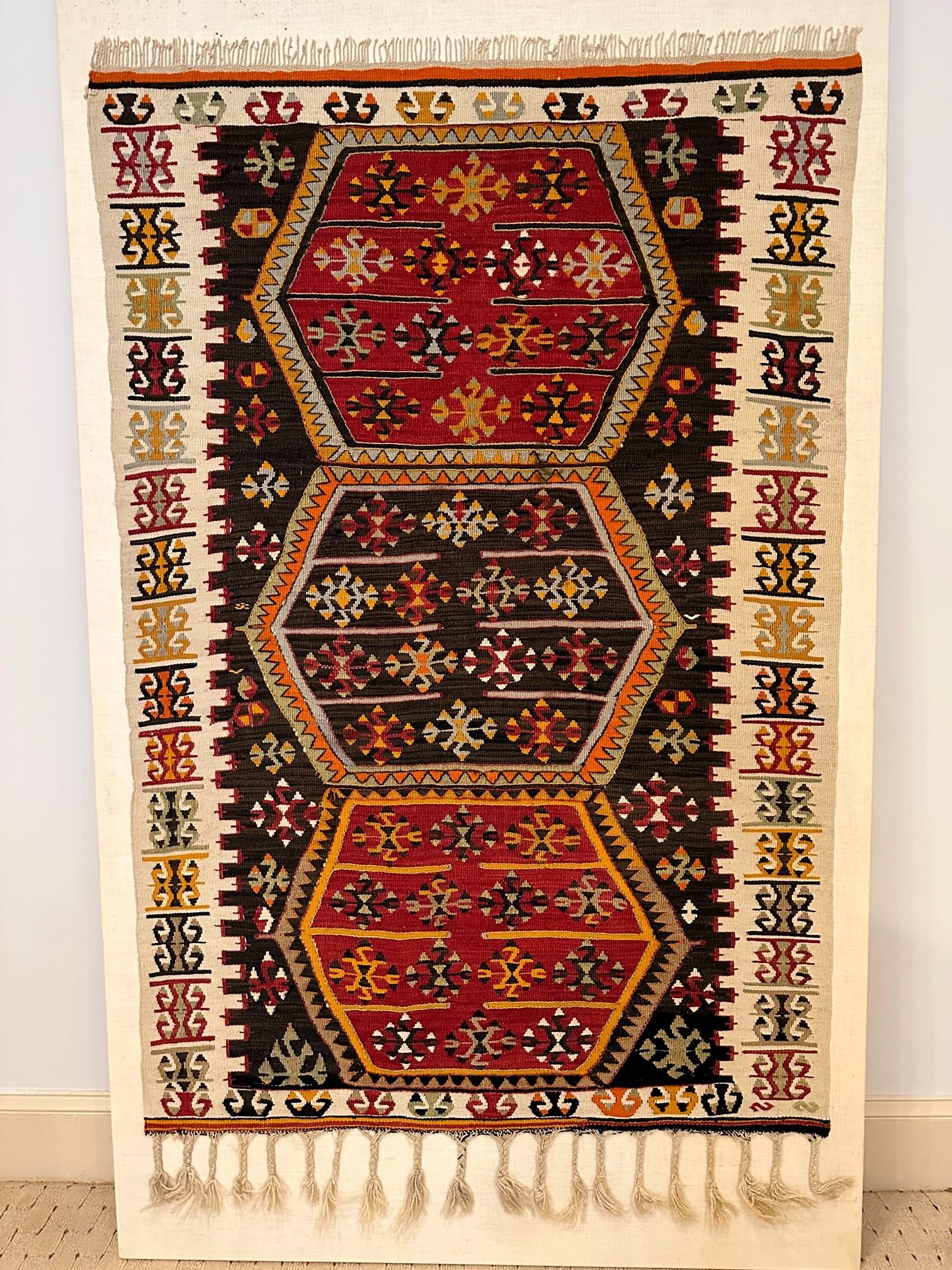 An antique Eastern Turkish wool kilim rug from Anatolia region circa 19th century. The finely woven rug is professionally mounted on a linen-backed canvas for display. The tribal weaving features three stacked hexagons in the center field with