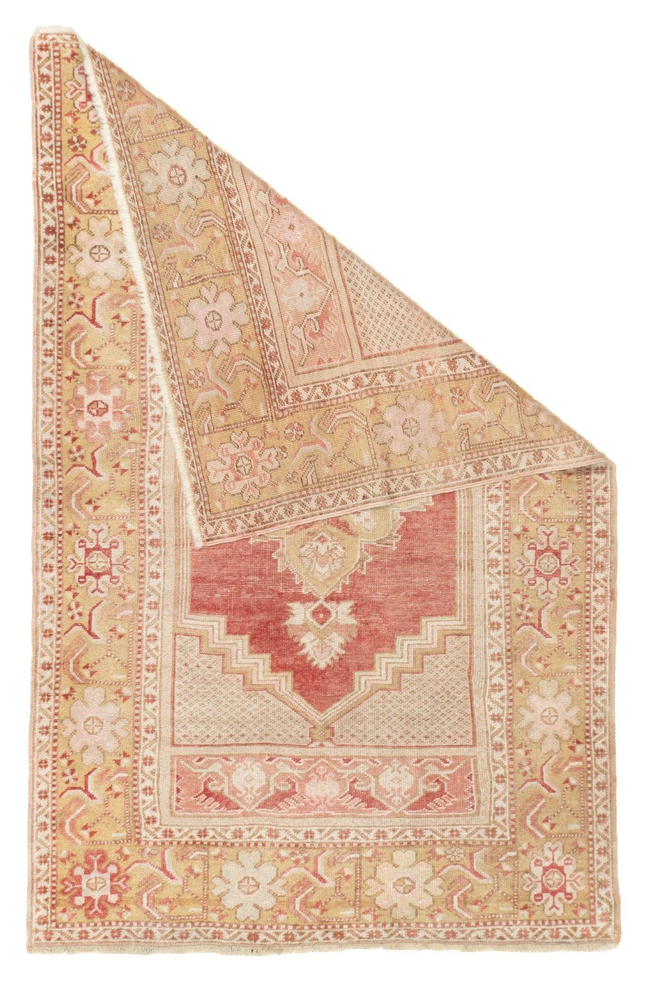 Alfombra antigua turca de Anatolia 3'4'' x 5'3''. El pequeño campo rojo abierto sostiene un medallón colgante de palmeta. Esquinas escalonadas de color crudo punteado y paneles adicionales en los extremos del campo que muestran secciones de bordes