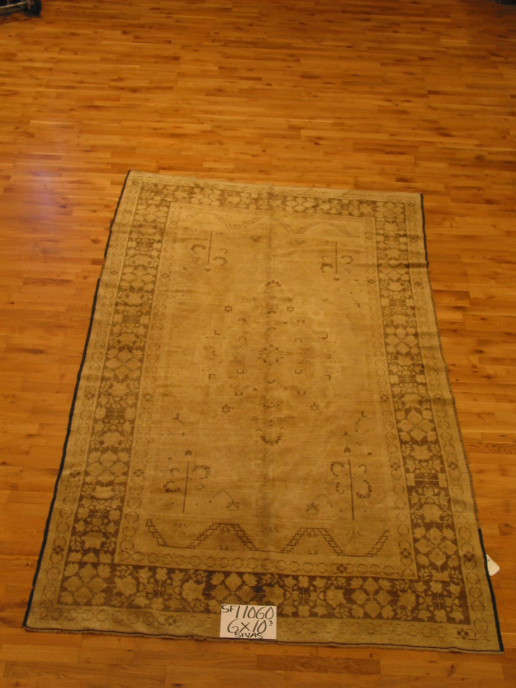 A finely balanced area rug featuring a beige/tan center panel with medallion and wide contrasting dark brown border frame. Dating back to the 1940s this gently used piece has the warm patina of quality and tradition that is the hallmark of Turkish