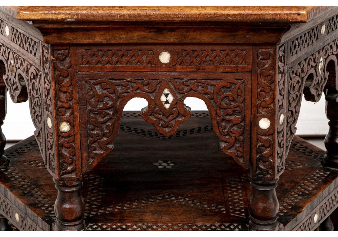 Hexagonal shaped, the carved top with a center star motif surrounded by calligraphic panels. The tiered frame with elaborately carved friezes with mother-of-pearl inlays. The lower tier also with a carved star. The lower inlaid frame with turned