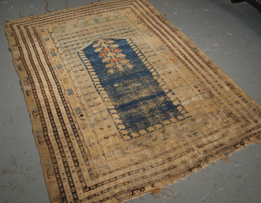 Antique Turkish Ghiordes prayer rug of scarce design of an early date
18th Century

The rug is beautifully drawn with a indigo blue central field which is surrounded by carnation flowers The field is framed by multiple borders

The rug is in poor