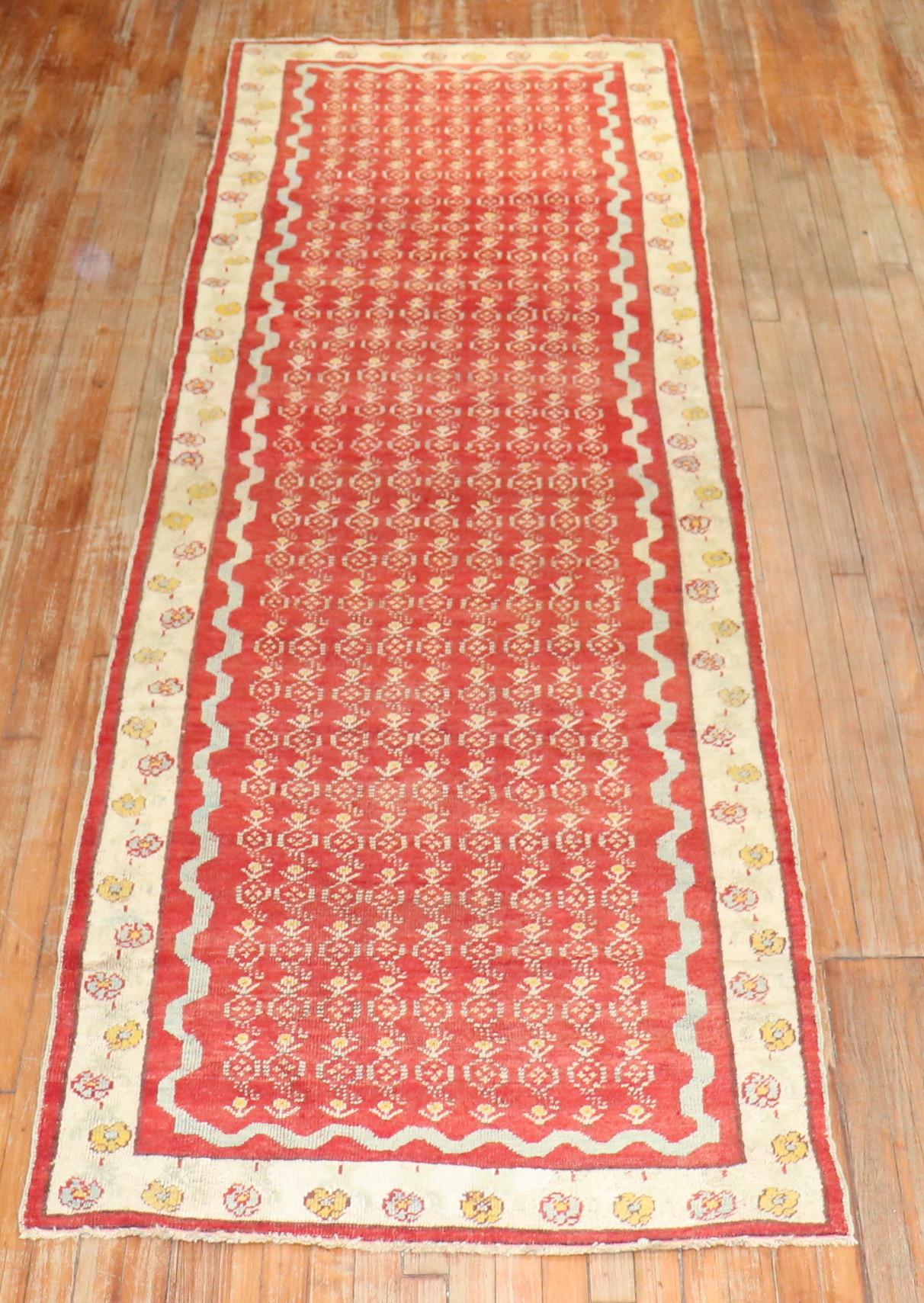 A vivacious antique Turkish Ghiordes runner. Floral in the field and border. The ground is red, the border is ivory, accents in light blue and goldenrod,

circa 1910. Measures: 3'6