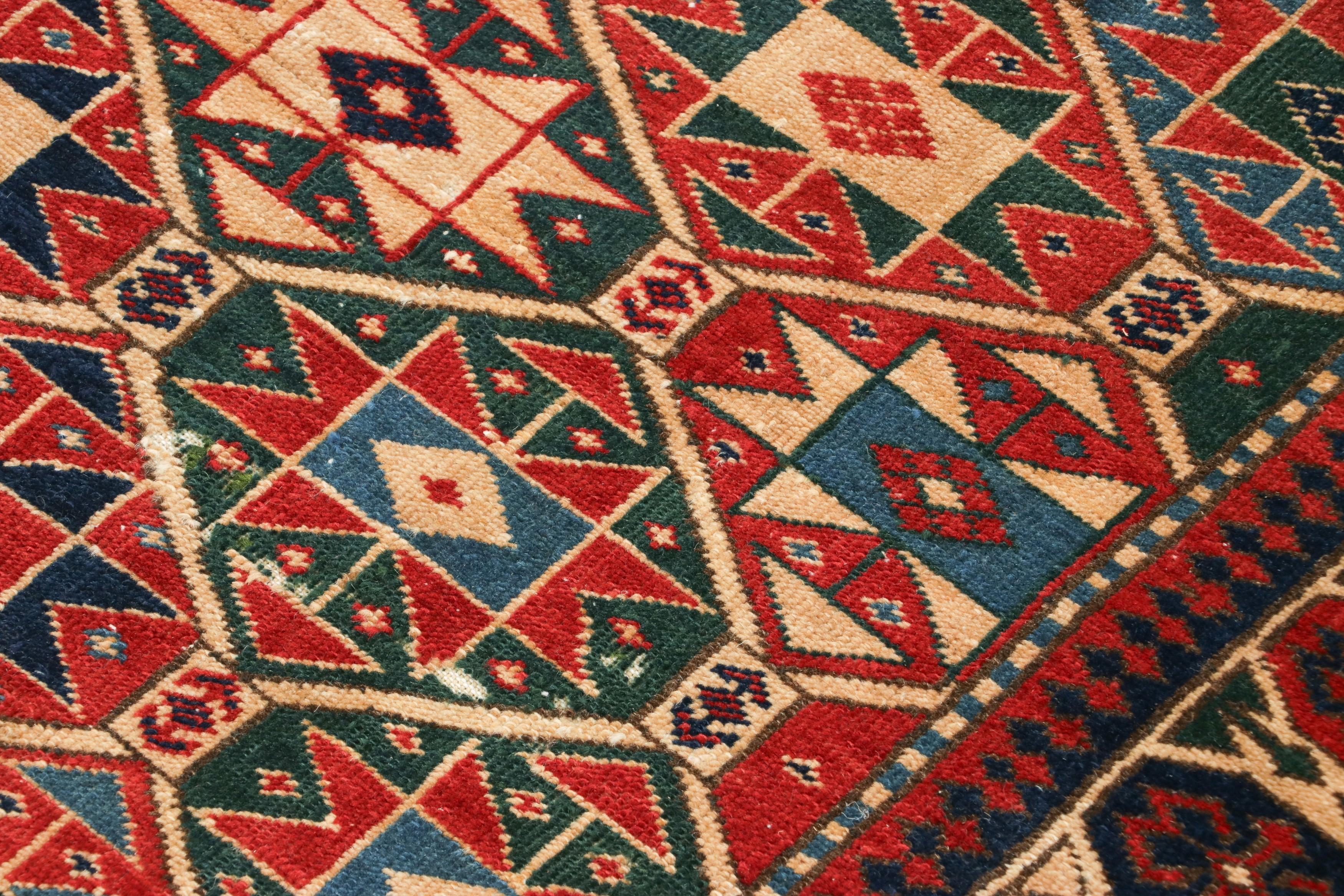Dieser atemberaubende handgeknüpfte Teppich aus der Kaukasusregion verkörpert die reichen Traditionen der Nomadenstämme des 19. Jahrhunderts, wie sie in Aserbaidschan oder Dagestan herrschen. Die kühnen geometrischen Muster und die leuchtenden