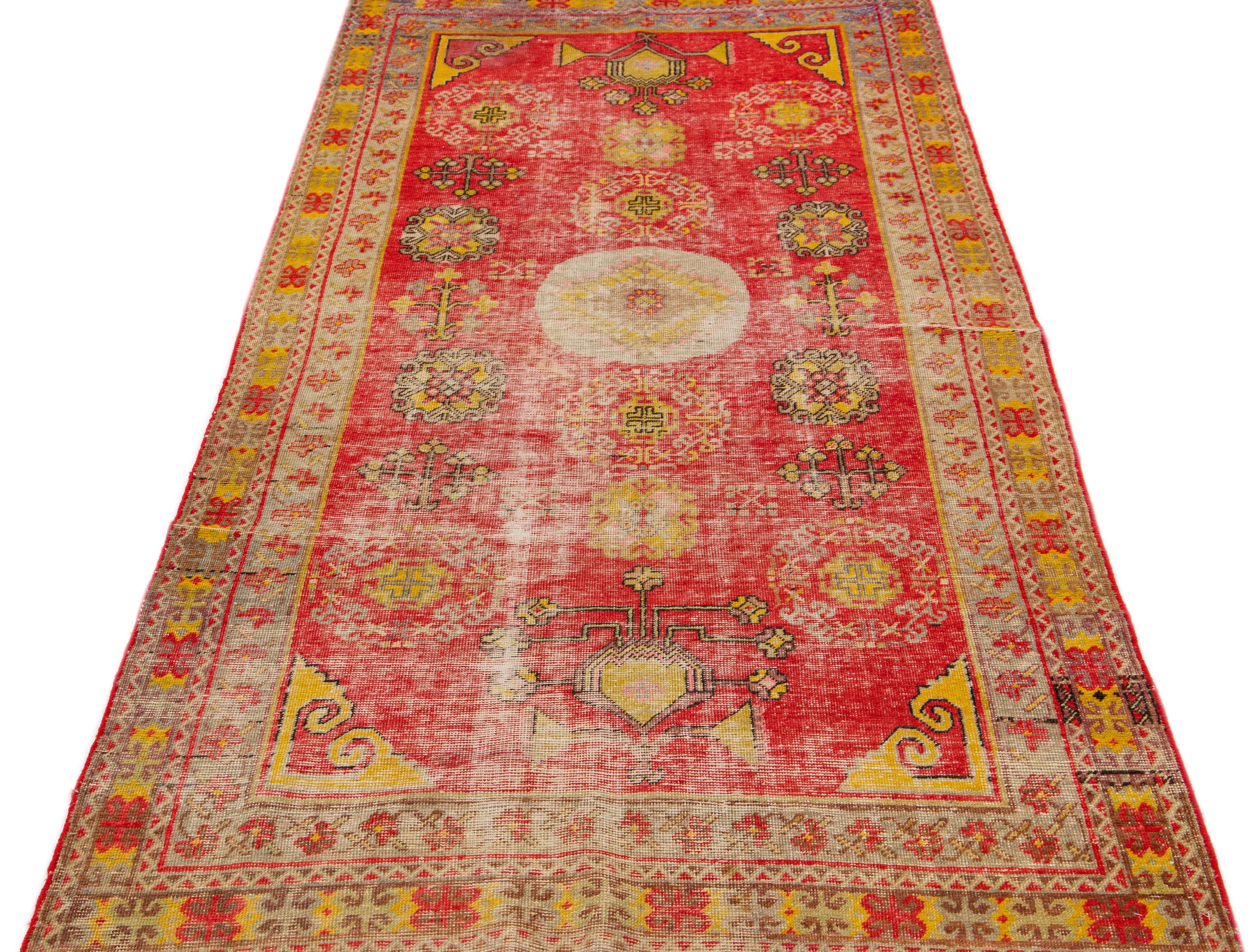 Beautiful Antique Turkish Khotan hand knotted wool runner with a red field. This Khotan runner has yellow, peach, and brown accents in a gorgeous all-over medallion floral motif design.

This runner measures 4'1