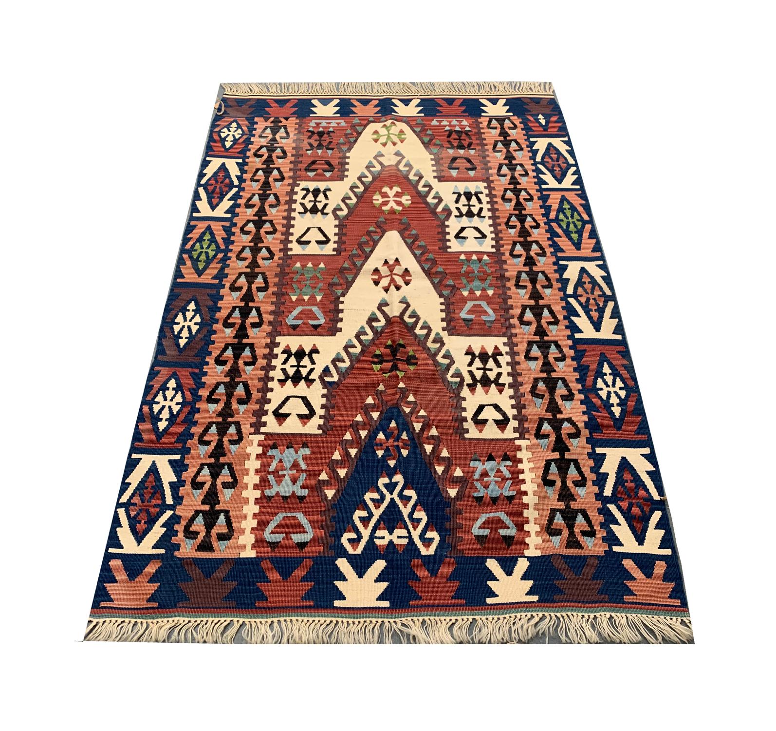 This antique Turkish Kilim rug is a striking example of tribal Anatolian flatweave artistry, featuring a bold central chevron motif surrounded by vivid geometric and symbolic tribal patterns. Handwoven from natural wool on a cotton foundation, it