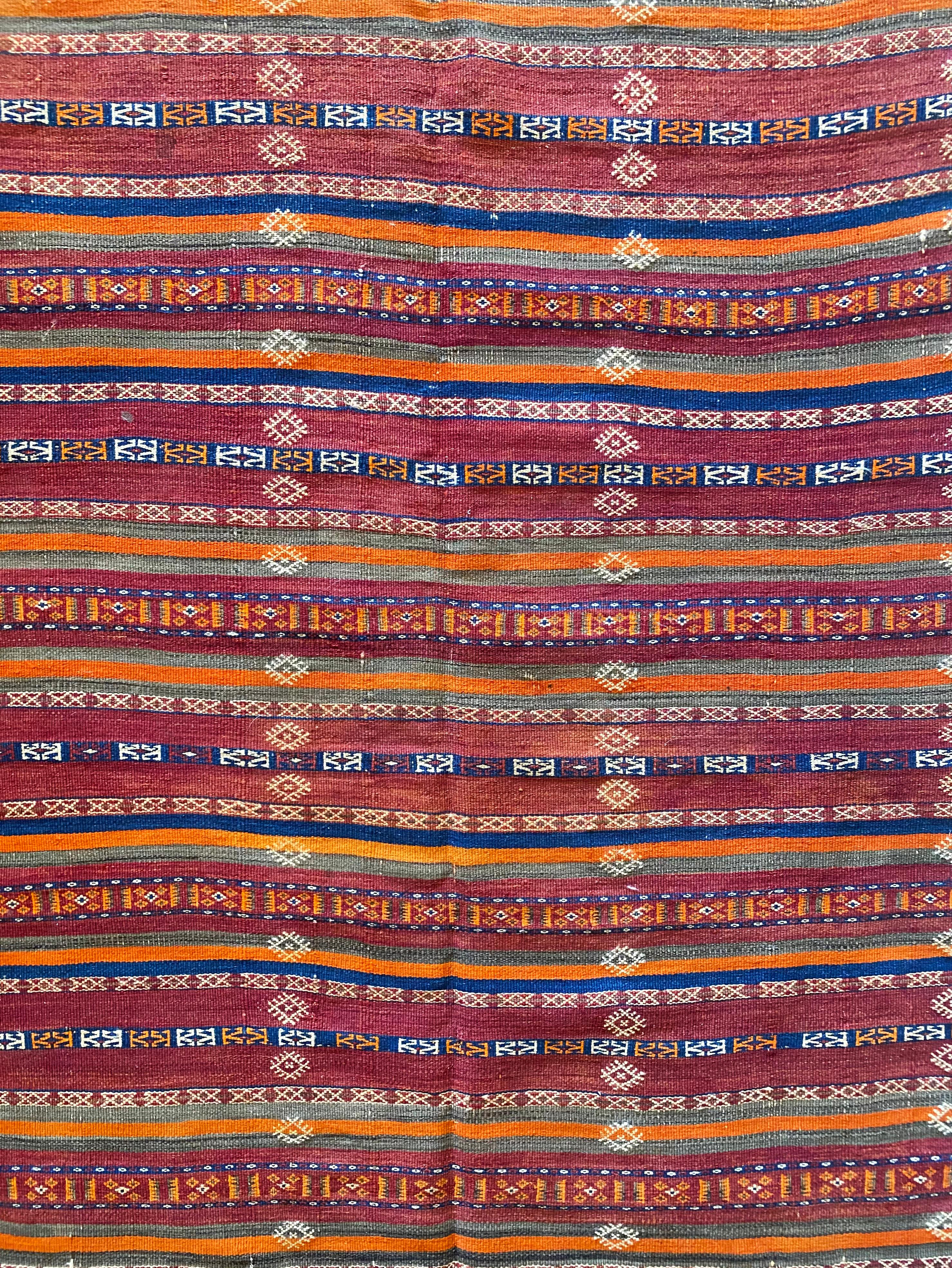 This Antique Turkish Kilim rug features a mix of orange, blue, red, and white dyed bands from wool and tribal motifs. 

Dimensions: Height 317cm x Width 140cm.