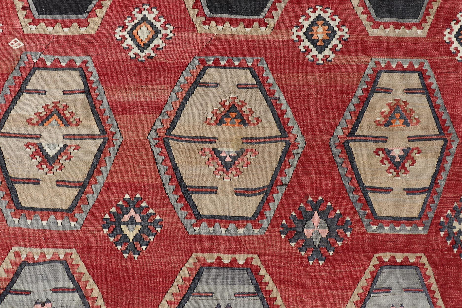 Maße: 8'8 x 12'2 
Dieser atemberaubende antike türkische Kilim-Teppich zeichnet sich durch ein lebhaftes Design mit verschlungenen sechseckigen Motiven vor einem satten roten Hintergrund aus. Der Teppich ist mit einer Reihe von Farben geschmückt,