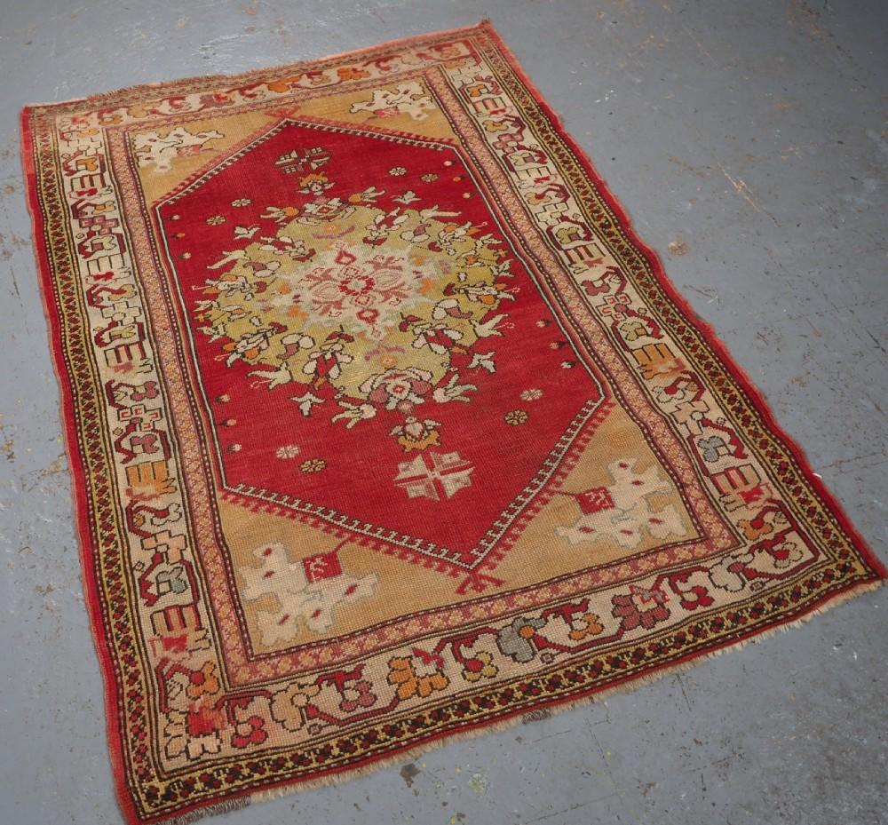 Antiker westanatolischer Milas-Teppich mit einem großen Medaillonmuster
CIRCA 1900

Der Teppich hat ein einzelnes großes florales Medaillon in sanften Pastellfarben auf einem klaren roten Grund. Der Teppich hat eine sanfte Farbpalette und hat auch