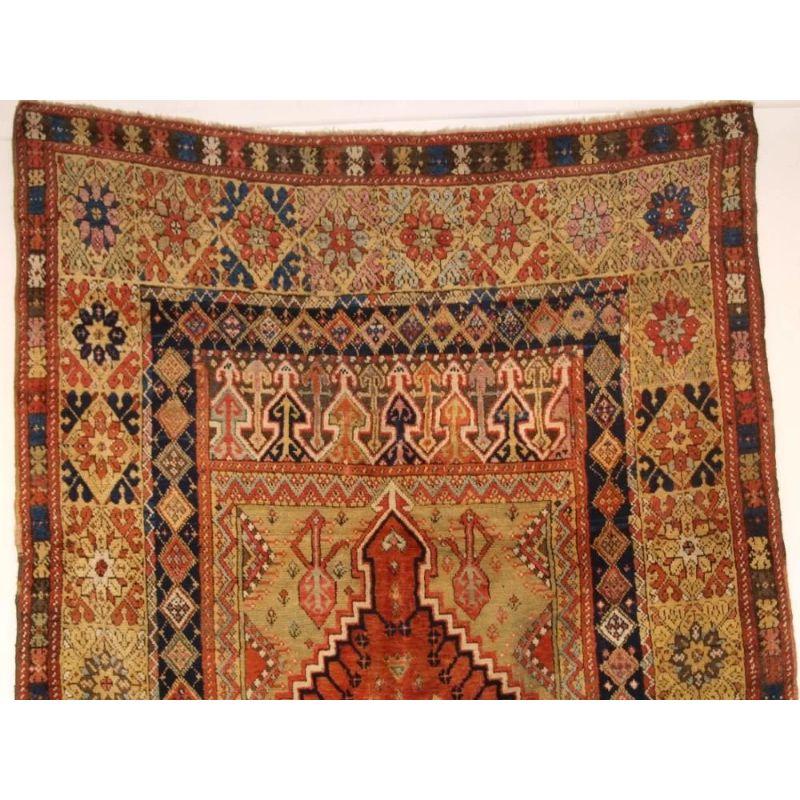 Antique Turkish Mujur prayer rug of classic design with a superb range of colours. Mujur is in central Anatolia, this rug is of a classic design for this town: the simple soft red central panel surrounded by a field of soft yellow / green, note the