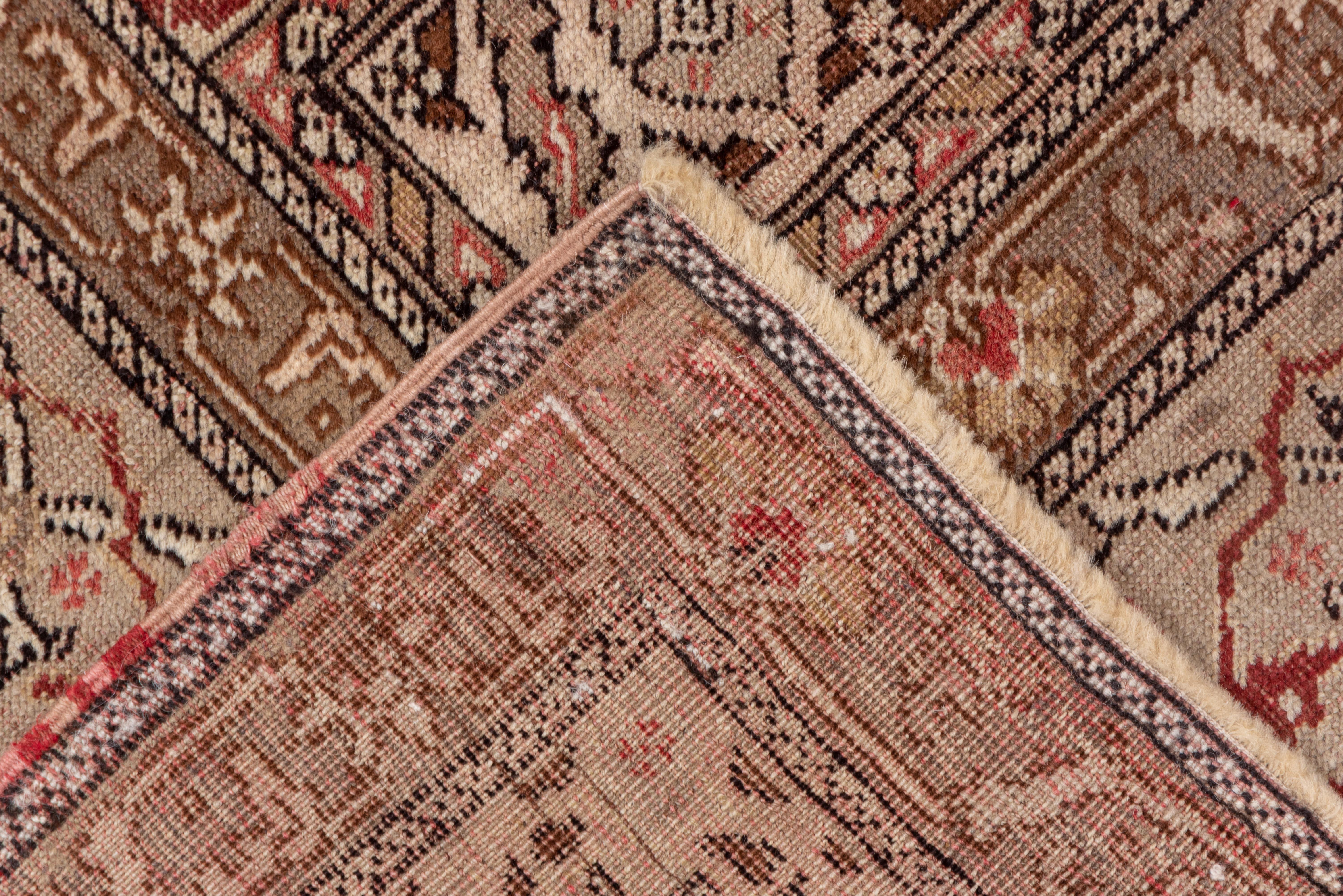 This well-woven Turkish urban scatter in the Persian Tabriz mode shows an ivory ground supporting a scalloped medallion with an old ivory rosette center and a surrounding vigourous vinery with lancet leaves, palmette and carnation pendants. Panels
