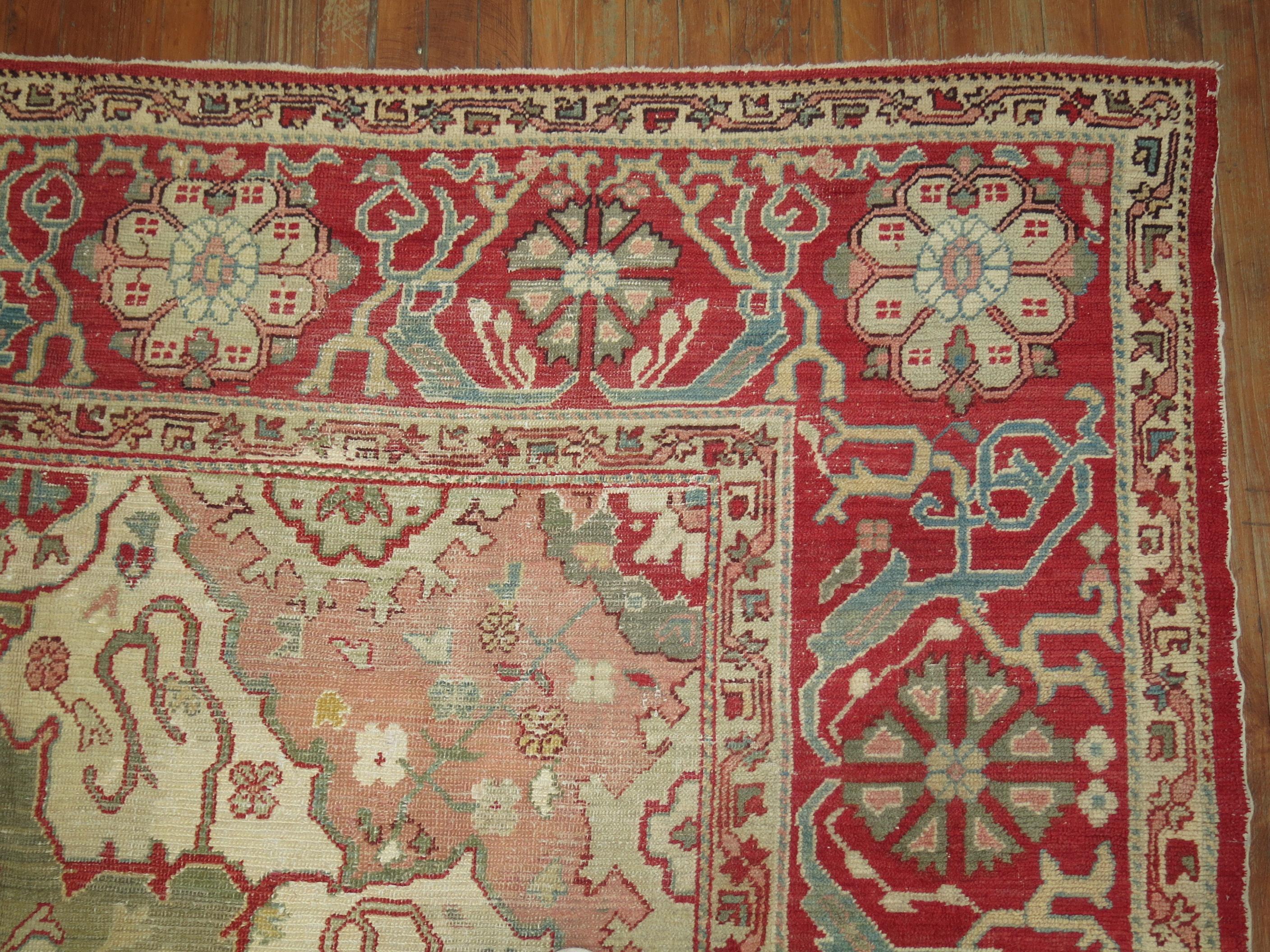 A highly decorative, artistic forest green colored ground Turkish Oushak with a cherry red medallion and border. Beautiful natural abrashes in multiple areas. The piece has been kept in great shape over the course of the past century,

circa 1900,