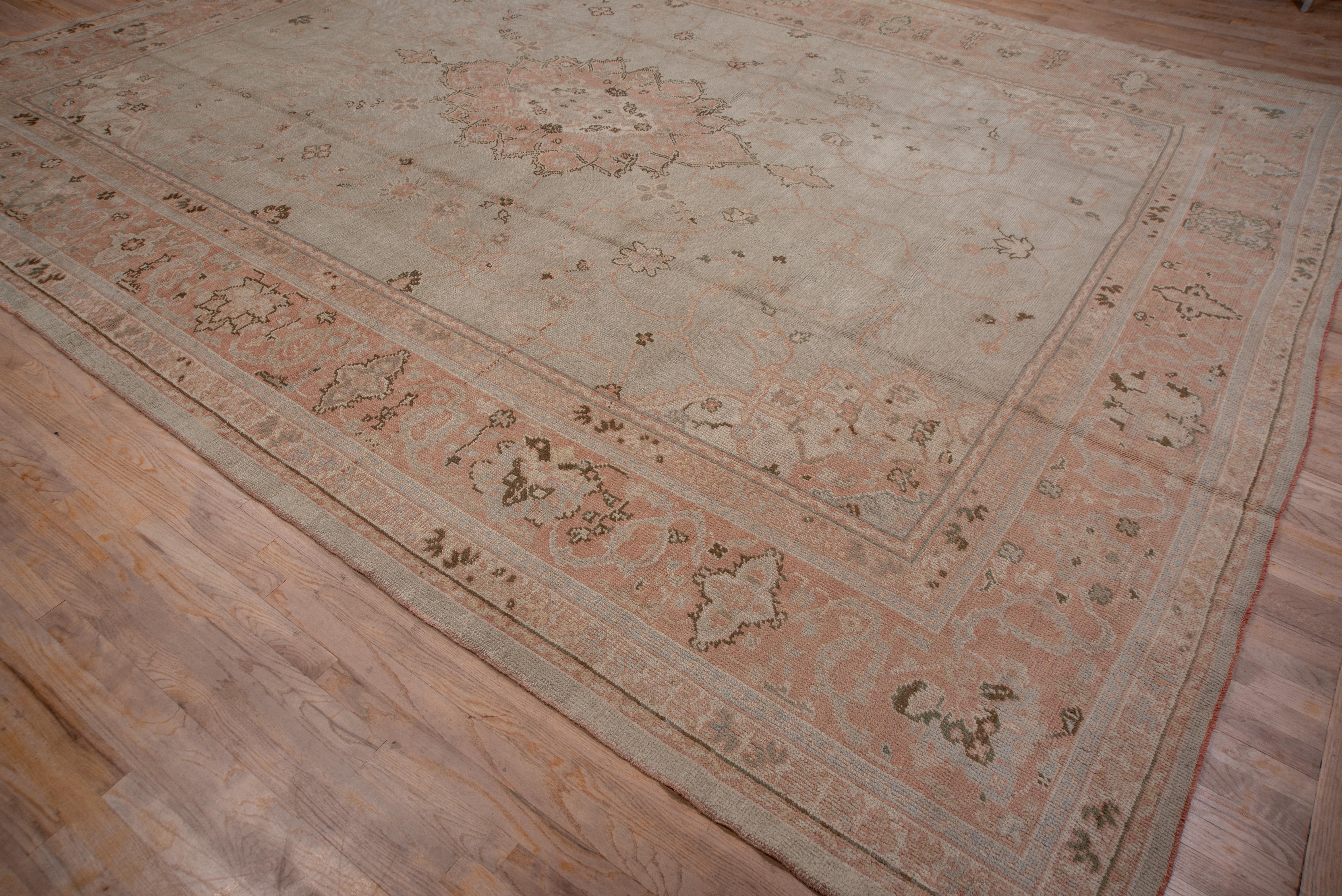 The chalk gray field displays a tall 16 point medallion and soft pink Sub-medallion, with lesser sprays, tendrils and tiny palmettes. Small ecru- accented corners and light brown cartouche and fat palmette border. Good condition with a light,
