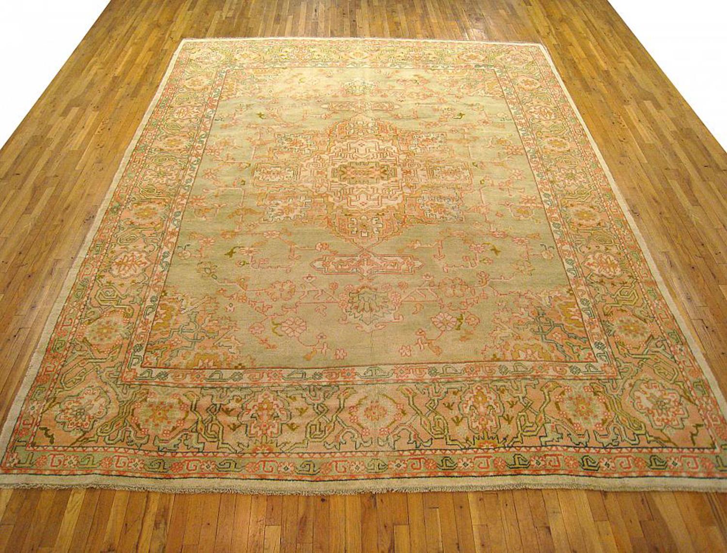 An antique Turkish Oushak oriental carpet, size 13'2 x 10'3, circa 1910. This lovely decorative carpet features a diffuse central medallion on a subtly hued central field, which is encased with a border of stylized floral elements. Hand-knotted,