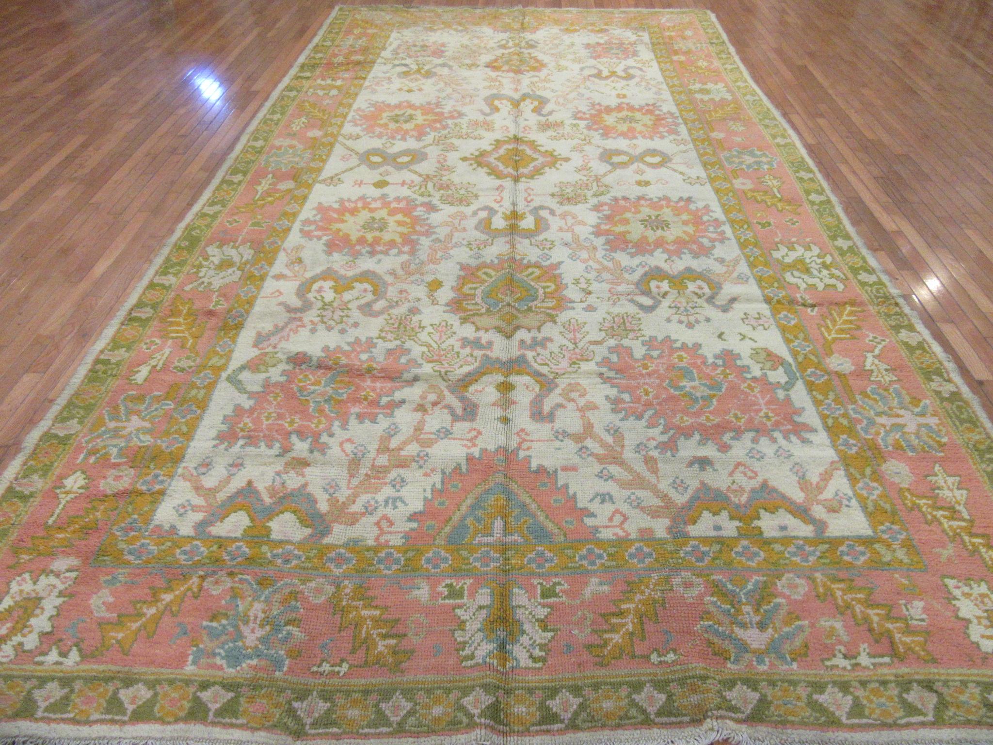 A beautiful example of the antique Turkish Oushak rugs in a hard to find wide gallery size. The rug has a simple all-over pattern on an ivory color field and salmon color border. It is in great condition. It measures 8' 6'' x 16'