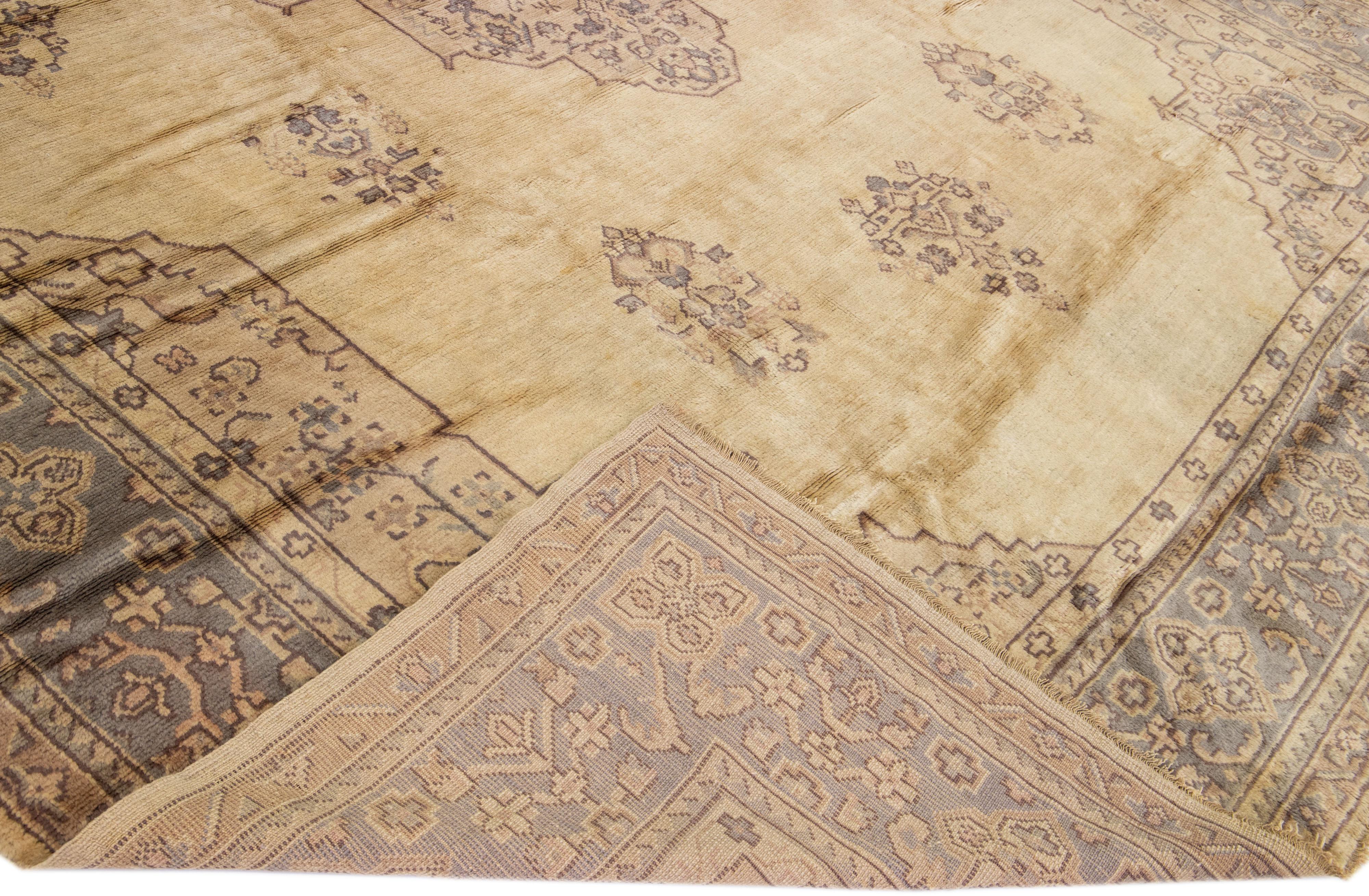 Magnifique tapis turc ancien en laine nouée à la main avec un champ beige. Ce tapis a un cadre gris et des accents dans un magnifique motif floral médaillon.

Ce tapis mesure : 11'9