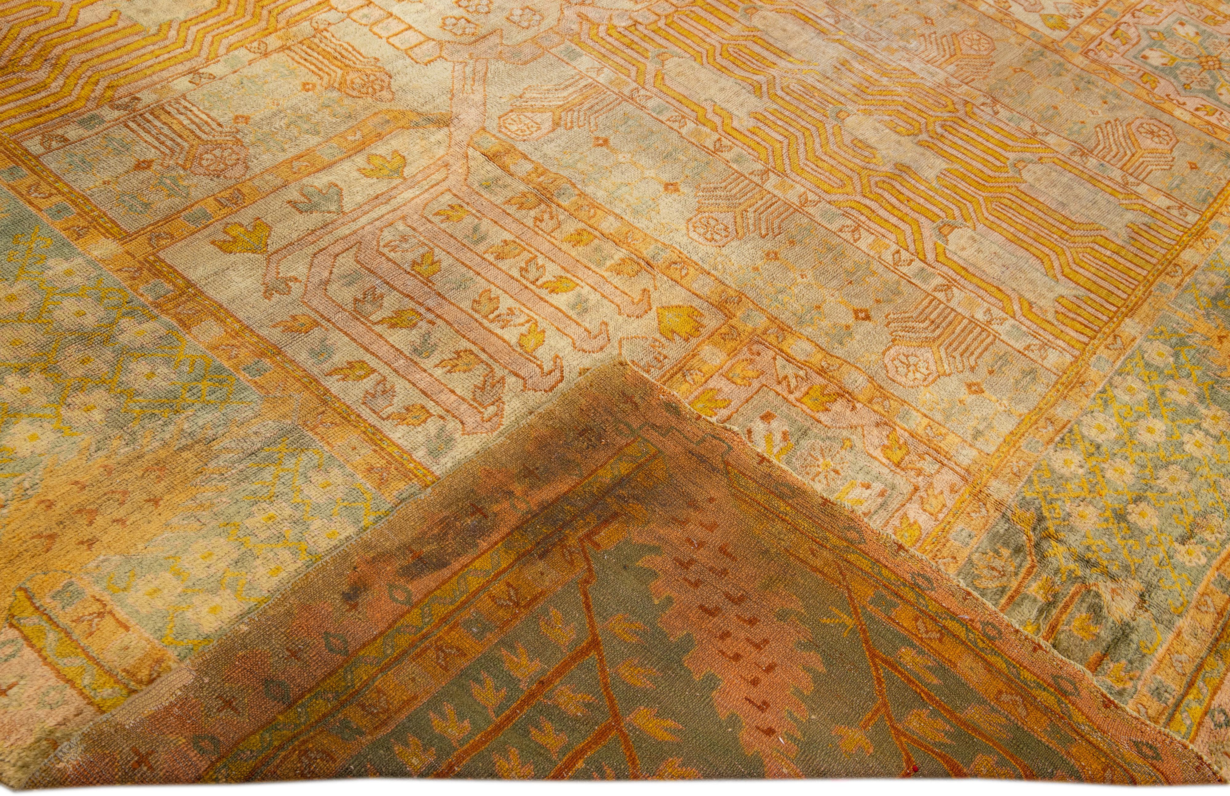 Beautiful Vintage Turkish hand-knotted wool rug with a Tan field. This rug has a designed green frame with accents of goldenrod and brown in a gorgeous all-over geometric floral design.

This rug measures: 11'10