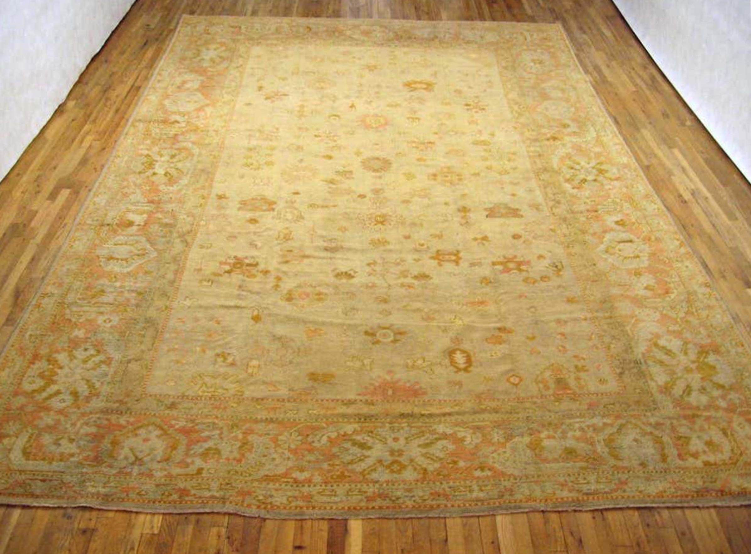 An antique Turkish Oushak carpet, circa 1900. Size: 17' x 11'. This lovely carpet has a variety of floral motifs across the softly hued central field. Enclosed within a festive border that gives this informal carpet even more of a sense of whimsy
