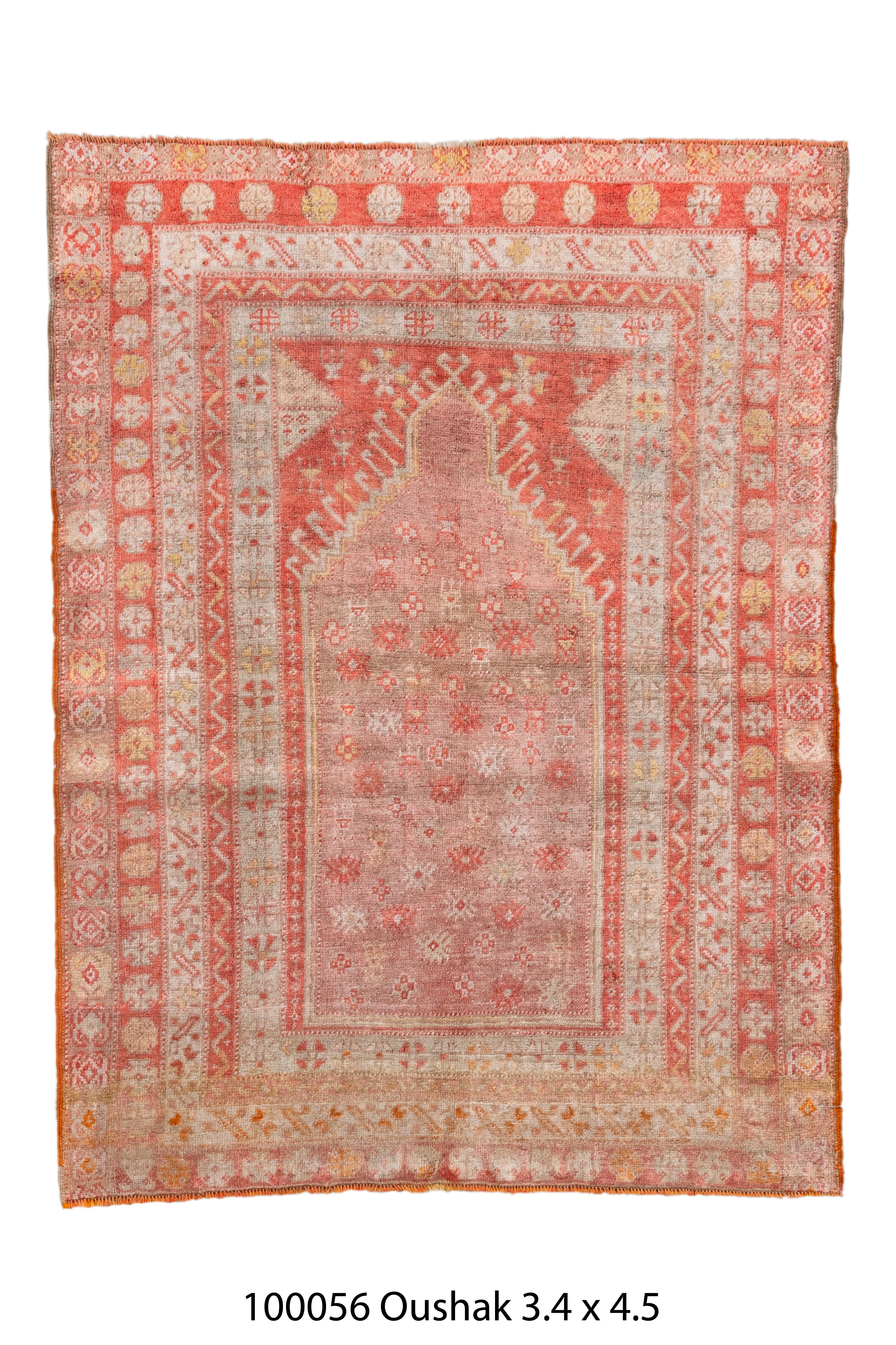 Lumineux tapis de prière antique turc Oushak présentant un motif de mihrab (niche de prière) richement décoratif. Le design est rendu en corail doux, terracotta délavé, or pâle, ivoire et touches de blush, offrant une palette de couleurs harmonieuse