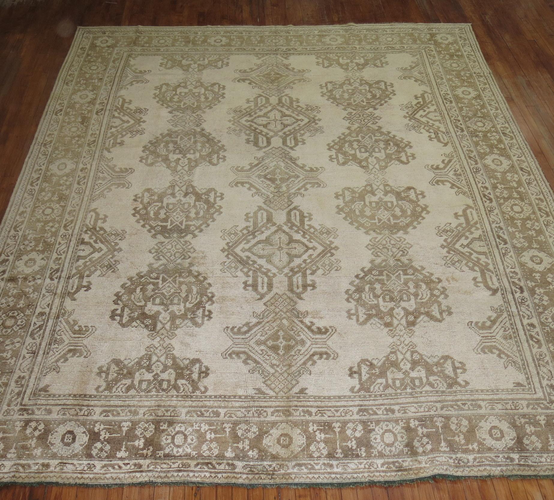 An early 20th century antique Turkish Oushak rug with a beige-colored ground, accents in brown

Measures: 9'9'' x 12'2''.