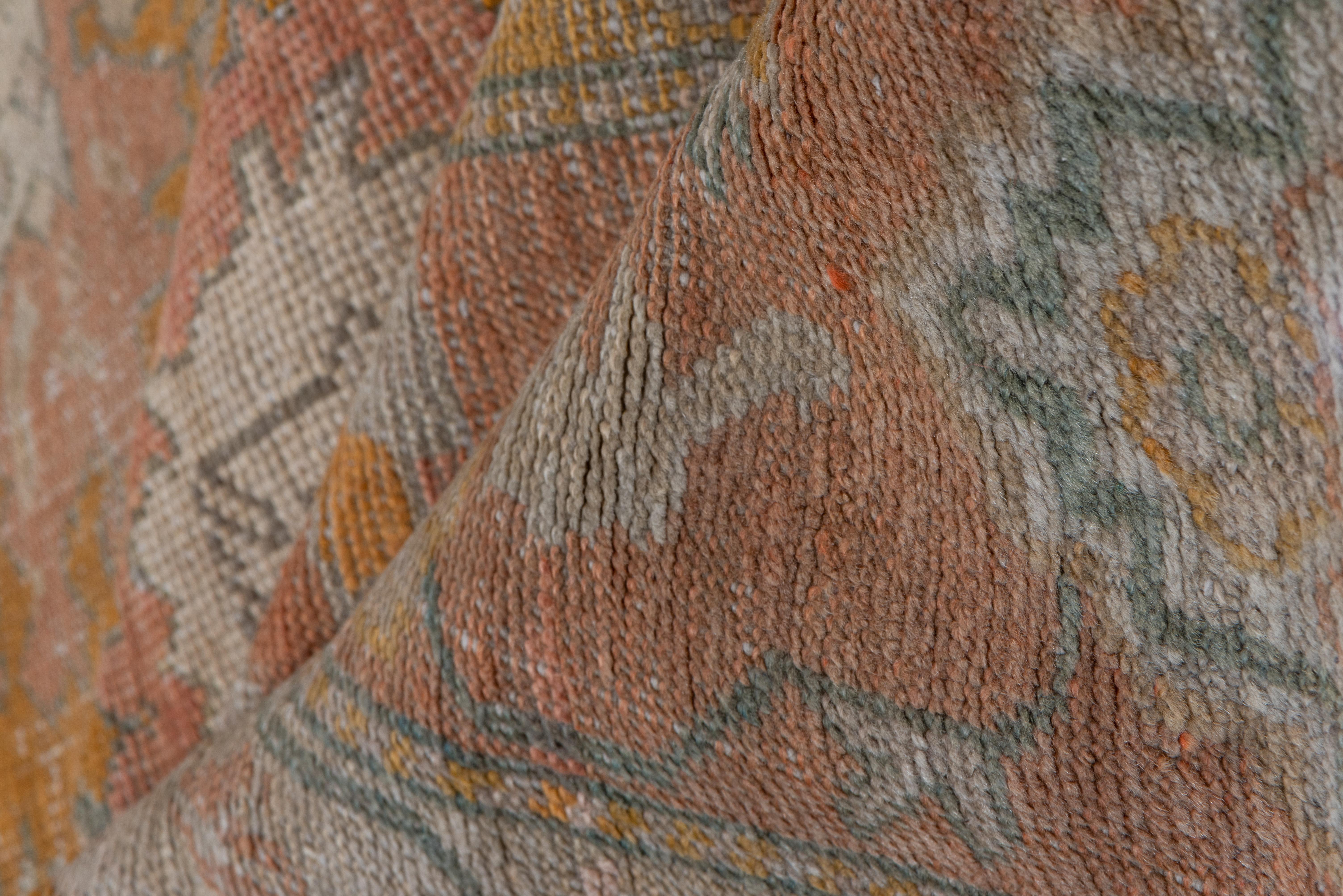 This orange field of this West Anatolian workshop carpet displays a version of the allover Harshang design of richly ragged palmettes and flame-edged rosettes, in a shrimp pink border of stepped cartouches in goldenrod, ecru and sand. Good condition