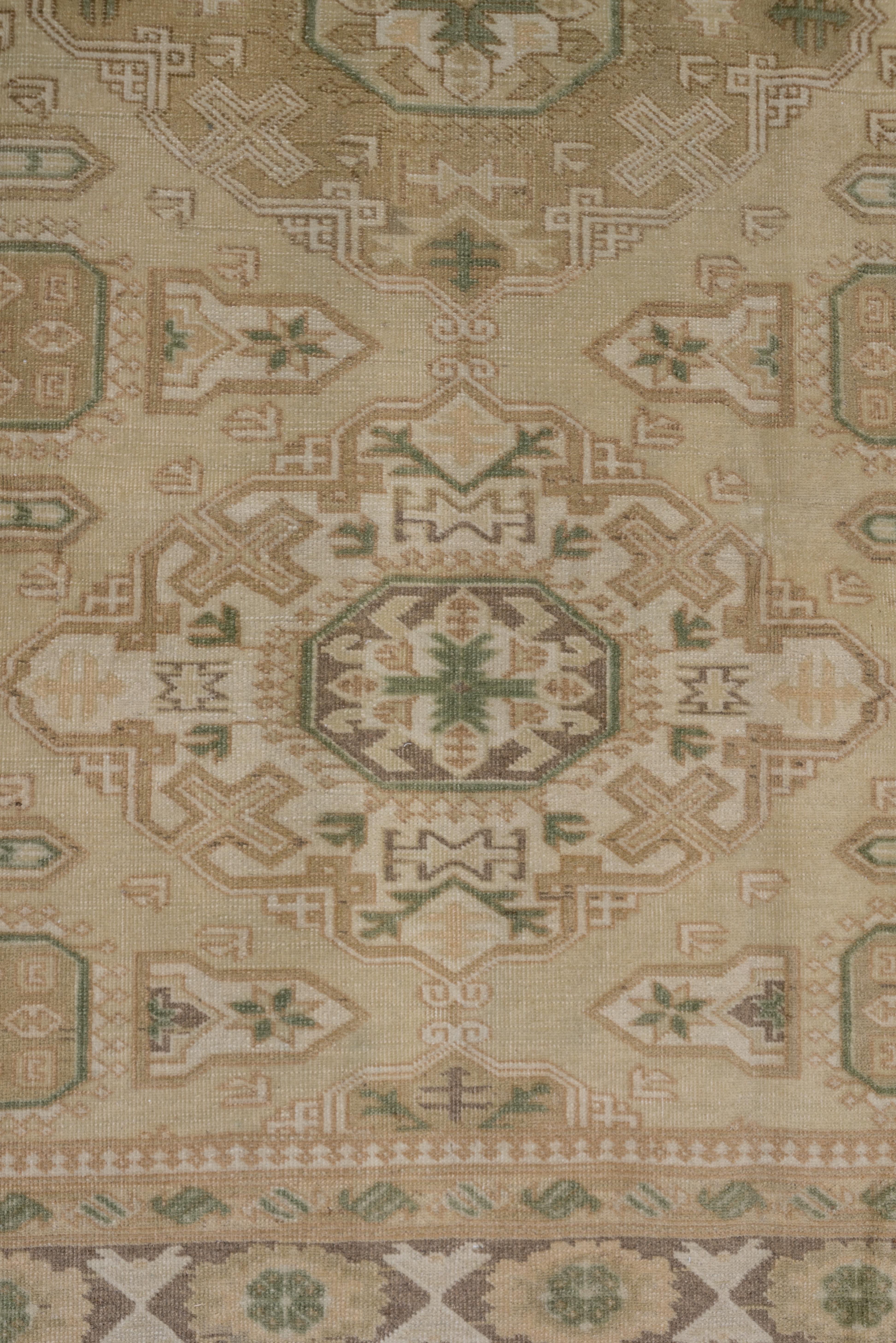 A close copy of a Caucasian sumak rug, this Turkish Oushakscatter shows three reticulated lozenge medallions in cream and buff on a camel-straw field. Supporting side octagons and 