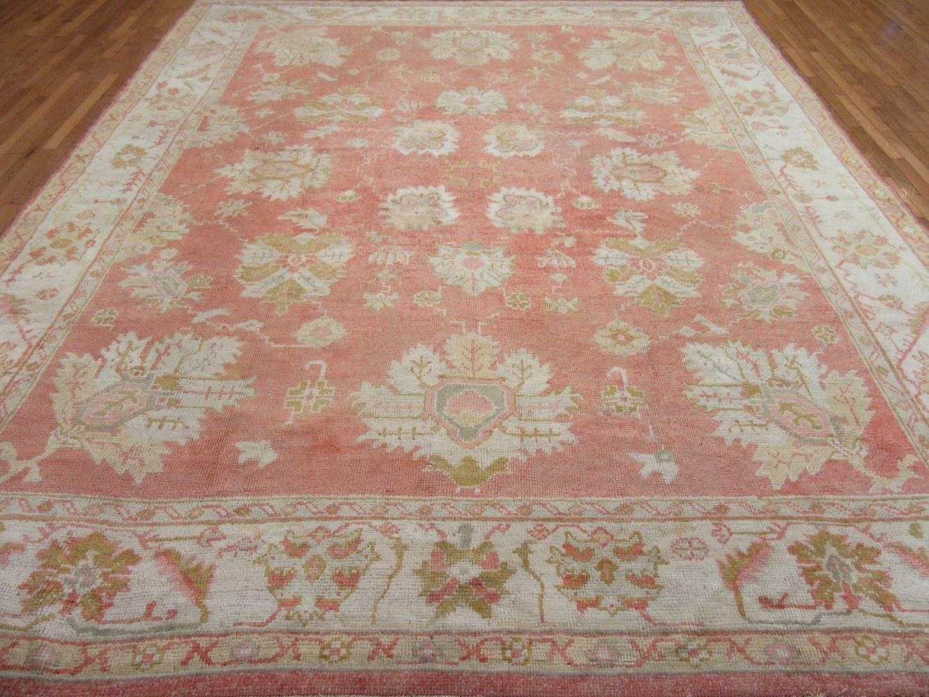 Turkish Oushak rugs are known for their larger scale simpler designs. This is an antique hand knotted Turkish Oushak with a simple all over pattern on a coral red field and ivory border. It is made with all fine wool colored with natural dyes. It