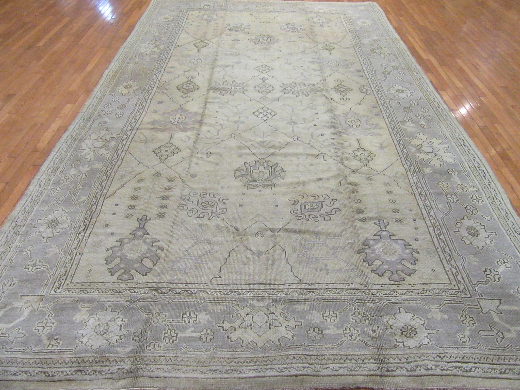 This is a beautiful and hard to find antique hand-knotted Turkish Oushak rug. It has an all-over trellis design on a soft ivory color field and gray border. The rug measures 8' 7