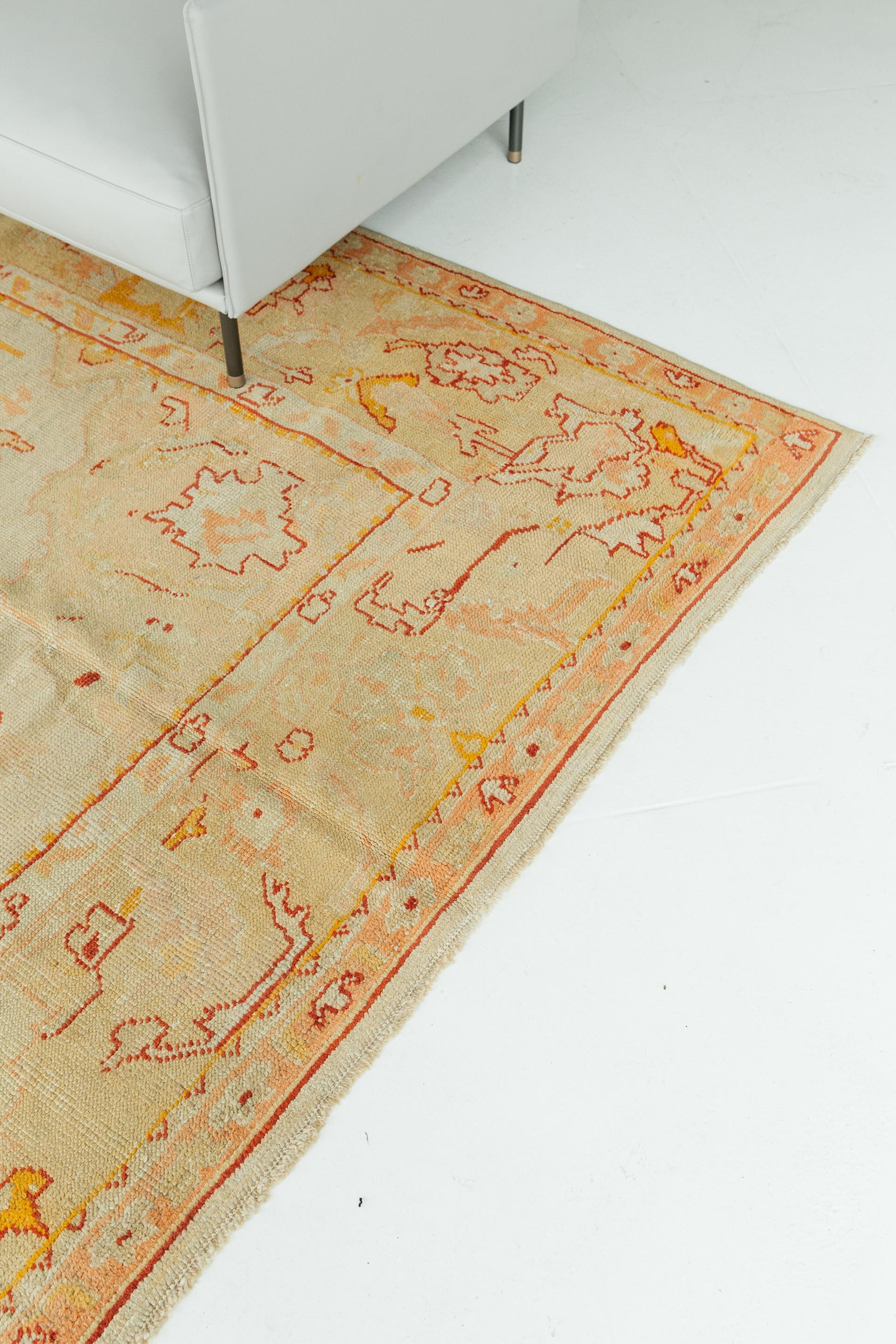 This intriguing antique Oushak has a subdued celadon field with pale saffron coloration in the grounds of the central medallion, spandrels and border. Additional colors include soft coral pink, vivid gold and deep red, used in the delineation of