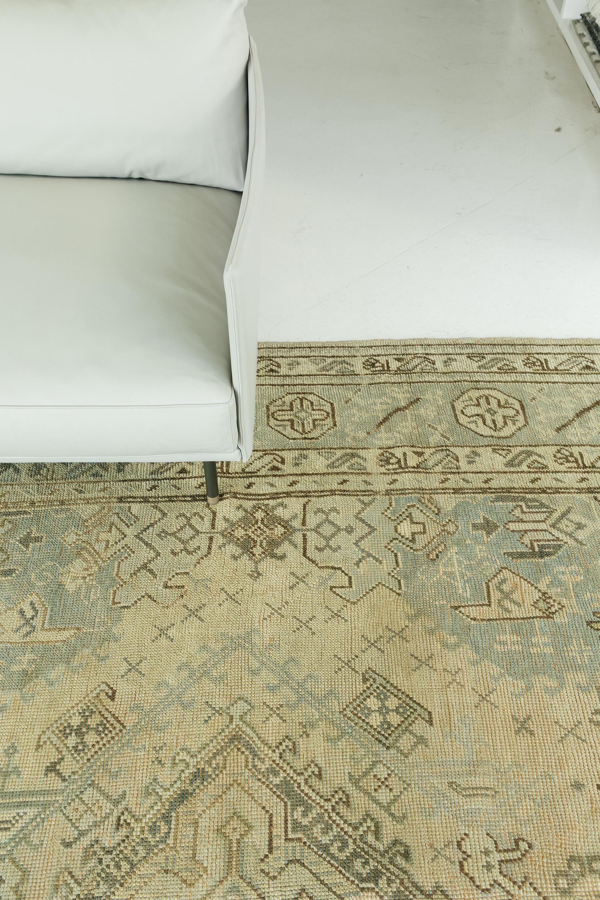 Antique Oushak in harmonious soft tones of ivory, celadon with umber. All-over, large scale drawing in the central field features tribal and geometric motifs in columns of repeating medallions. Border motifs, highly abstracted, include rosettes and