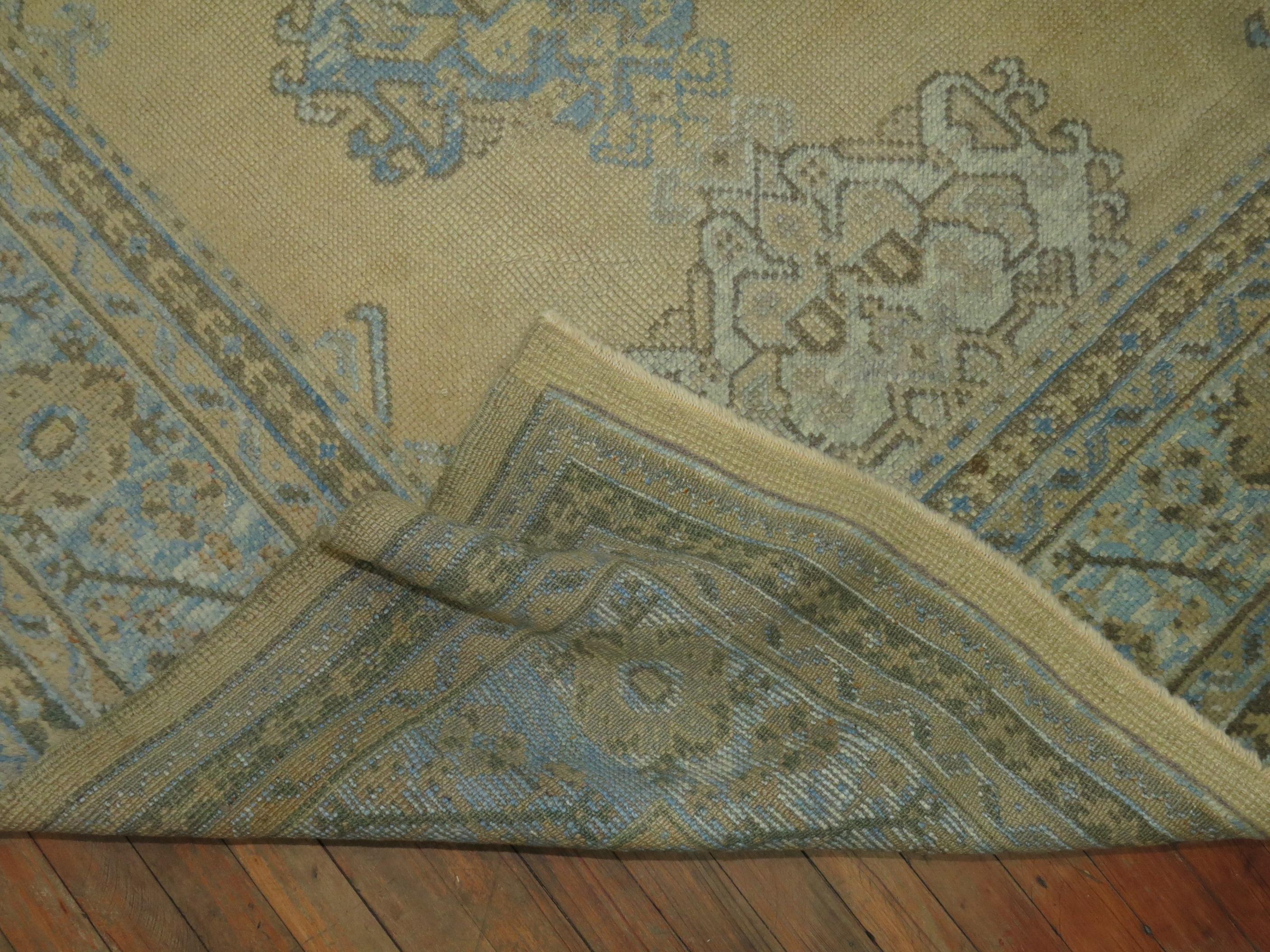 An early 20th century antique Turkish Oushak rug with a sand colored ground, powder blue border, accents of light blue brown and soft green. Measures: 9'1'' x 11'8''. Pictures from light and dark side.