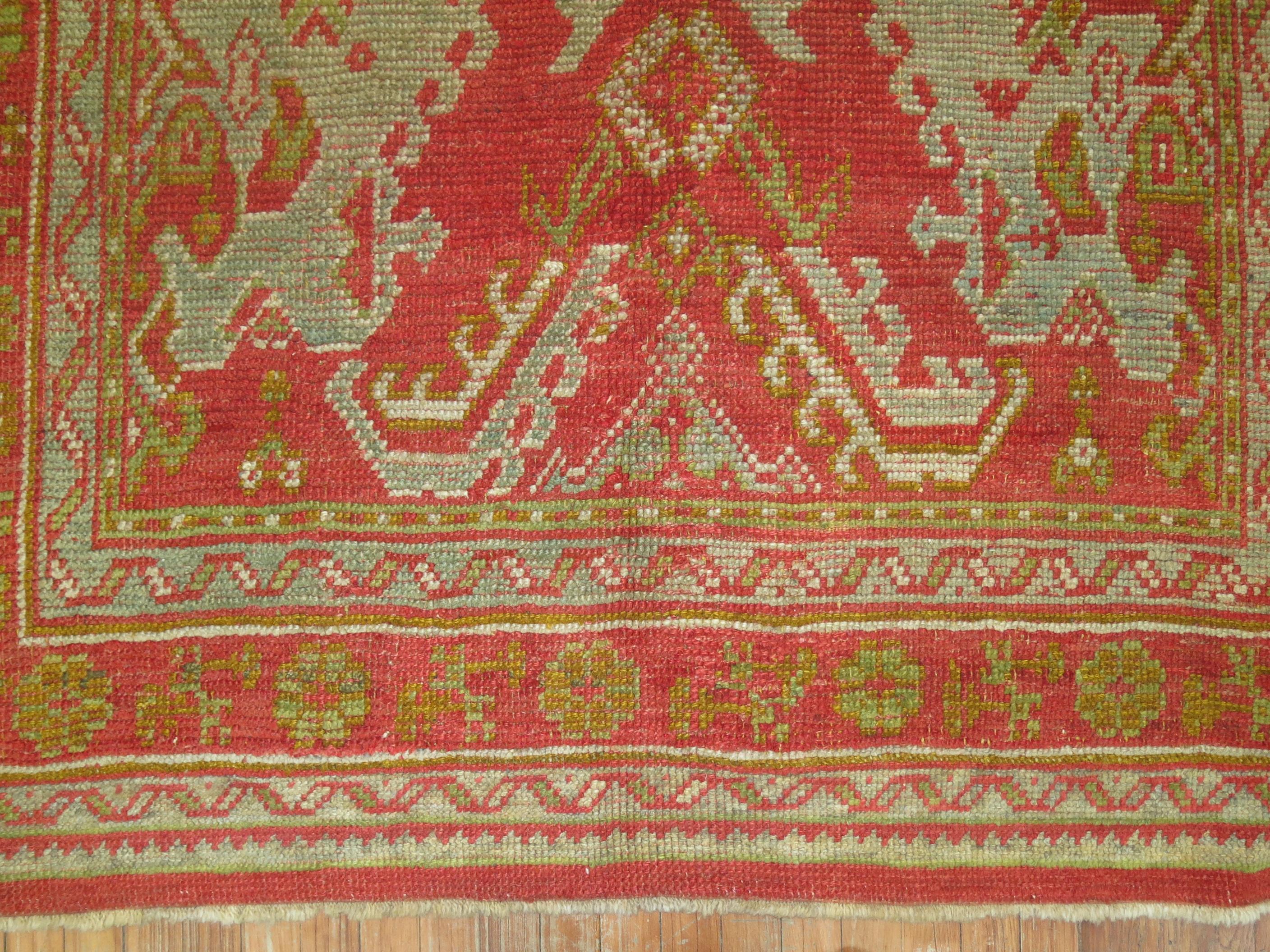 An authentic Turkish Oushak rug. Red field, accents in green, gray and blue.