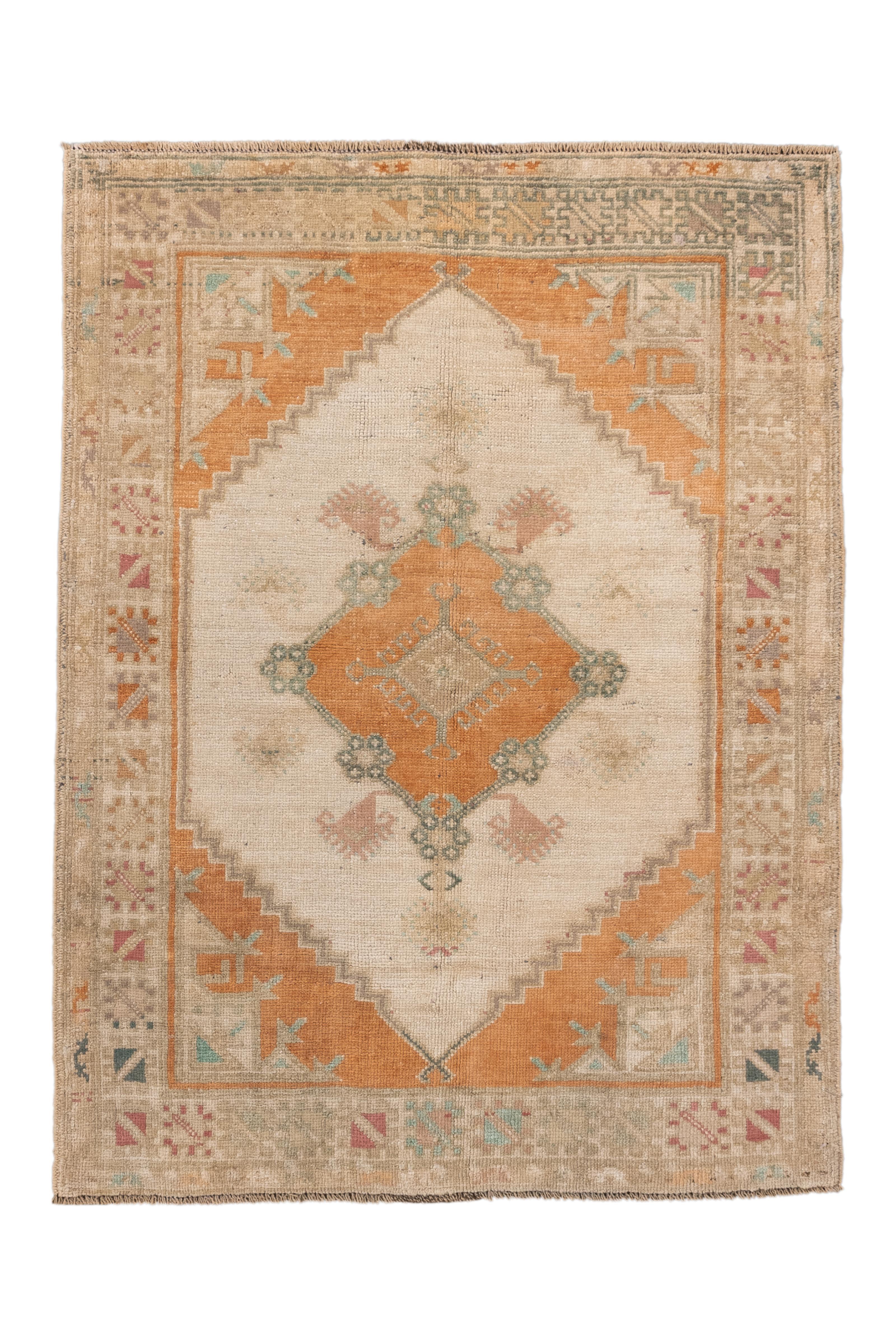 Ce charmant petit tapis antique Oushak présente un audacieux médaillon central en forme de diamant rendu en orange abricot doux, sur un champ crème chaud avec de délicats abrash. Des motifs angulaires en sarcelle pâle, rose et beige apportent un