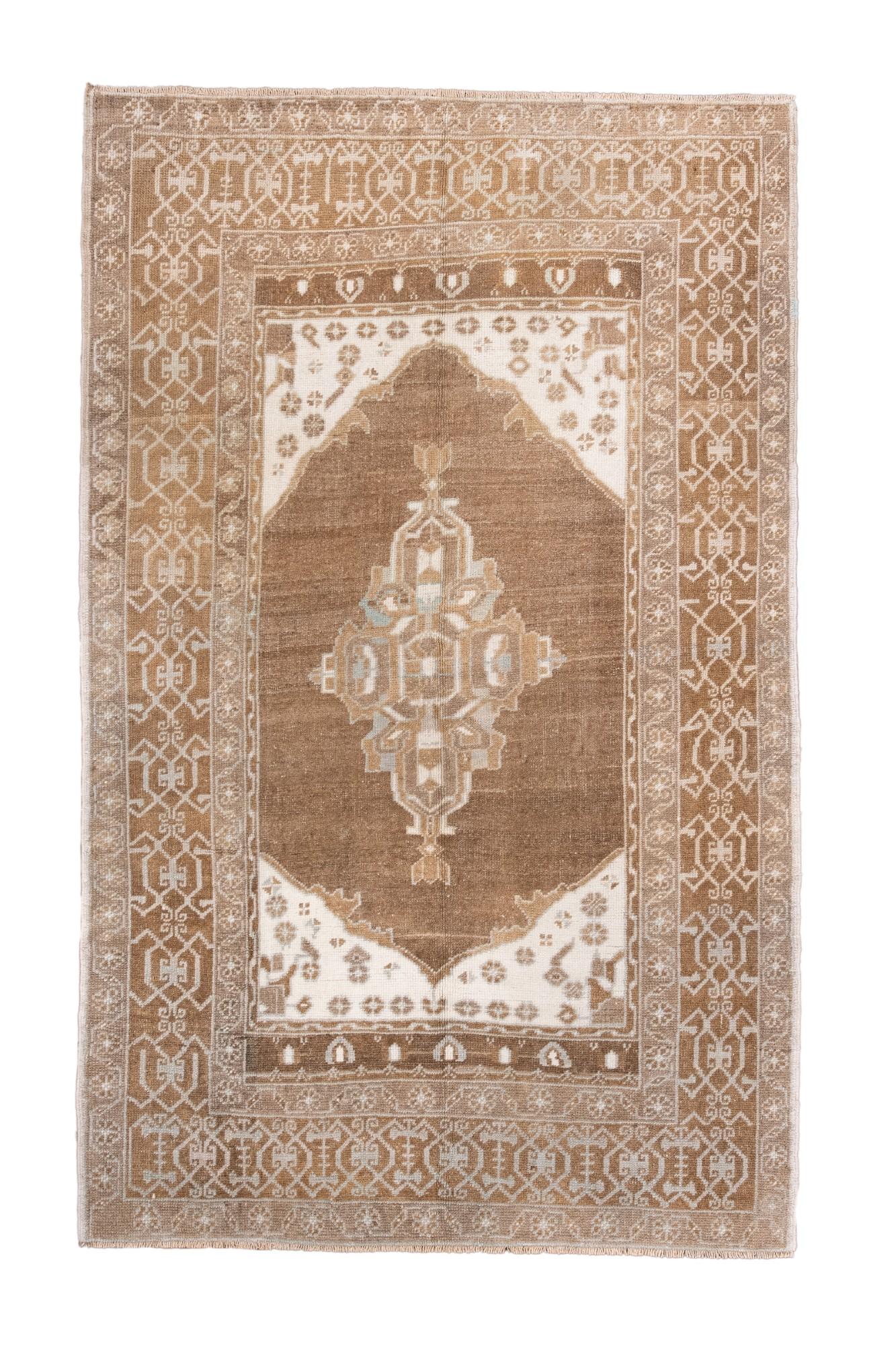 Dieser antike Oushak-Teppich zeigt ein großes zentrales Medaillon auf einem warmen taupefarbenen Feld mit elfenbeinfarbenen Eckzwickeln und zarten blassblauen Akzenten. Die Bordüre zeigt klassische geometrische Oushak-Motive in einer sanften,