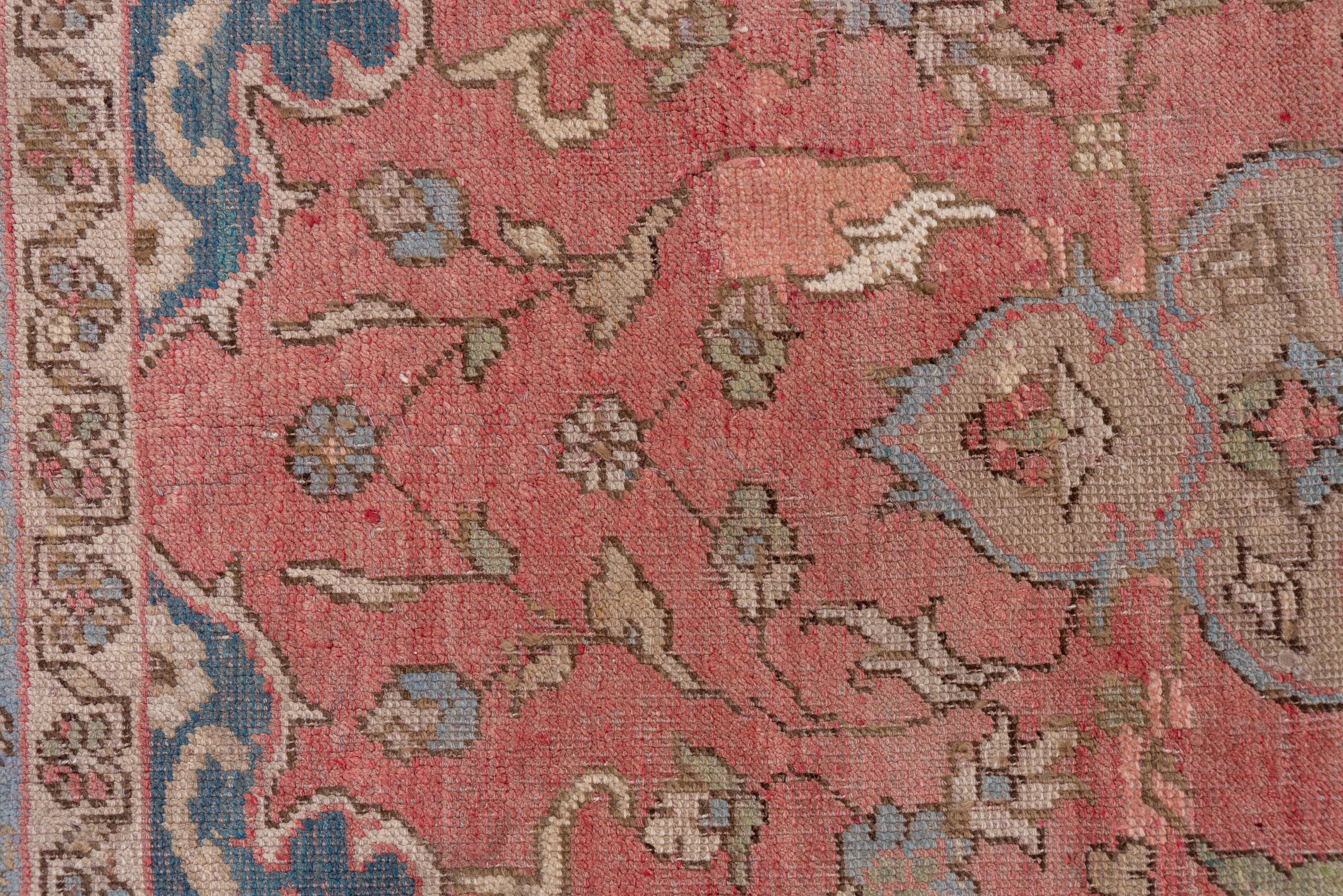 Dieses mäßig dicht gewebte Stück aus einer westtürkischen Werkstatt zeigt ein zartes, rosafarbenes Feld, in dessen Zentrum ein hängendes Stroh-Oktogramm-Medaillon mit einem hellblauen Oktofolien-Submedaillon steht, das sich dem Stil der persischen