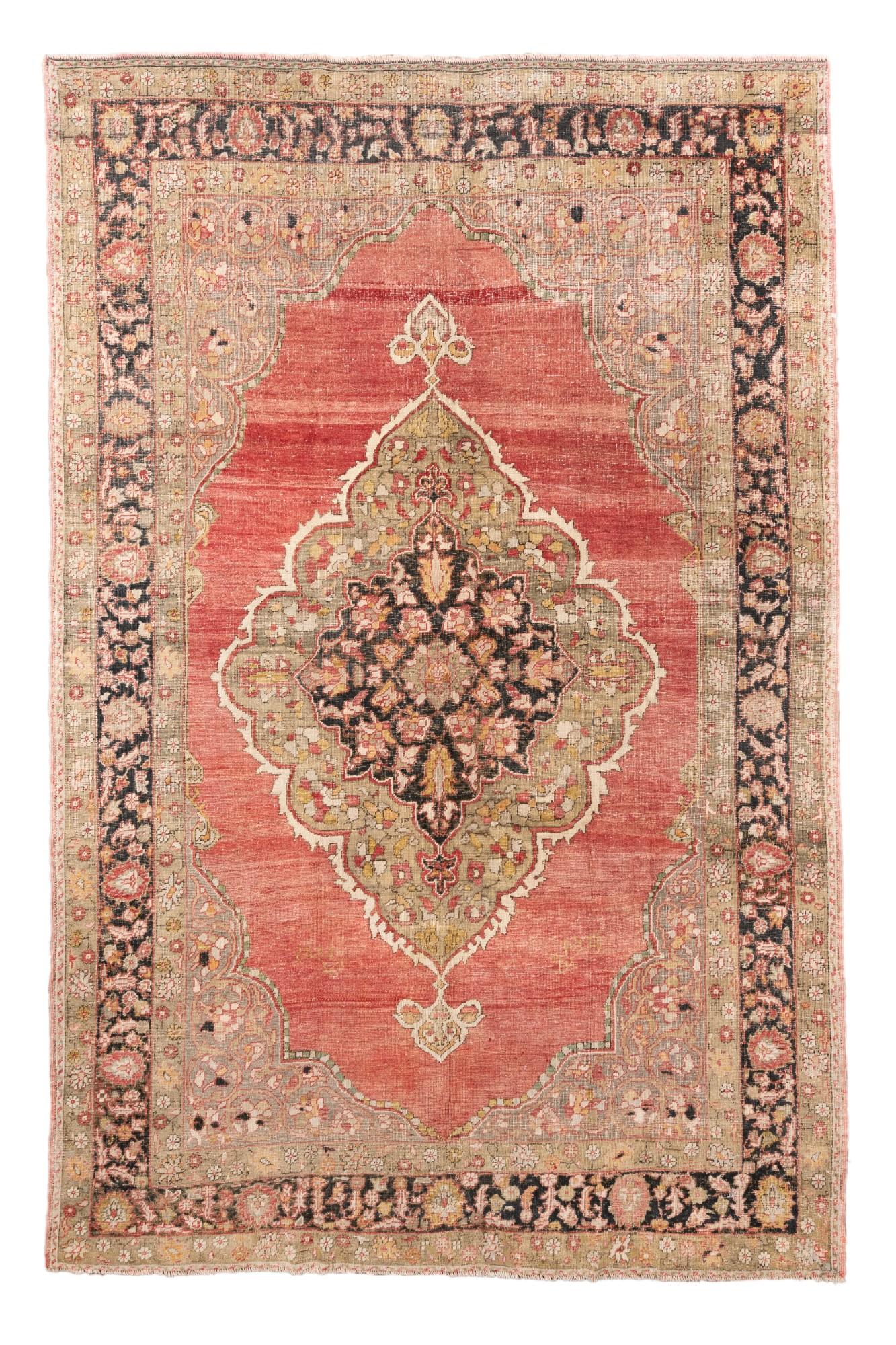 Ce remarquable tapis antique Oushak, datant d'environ 1900, présente un médaillon central richement stratifié dans des tons de noir, de corail et de sauge sur un champ de terre cuite rouge. La grande bordure de palmettes en anthracite et rose