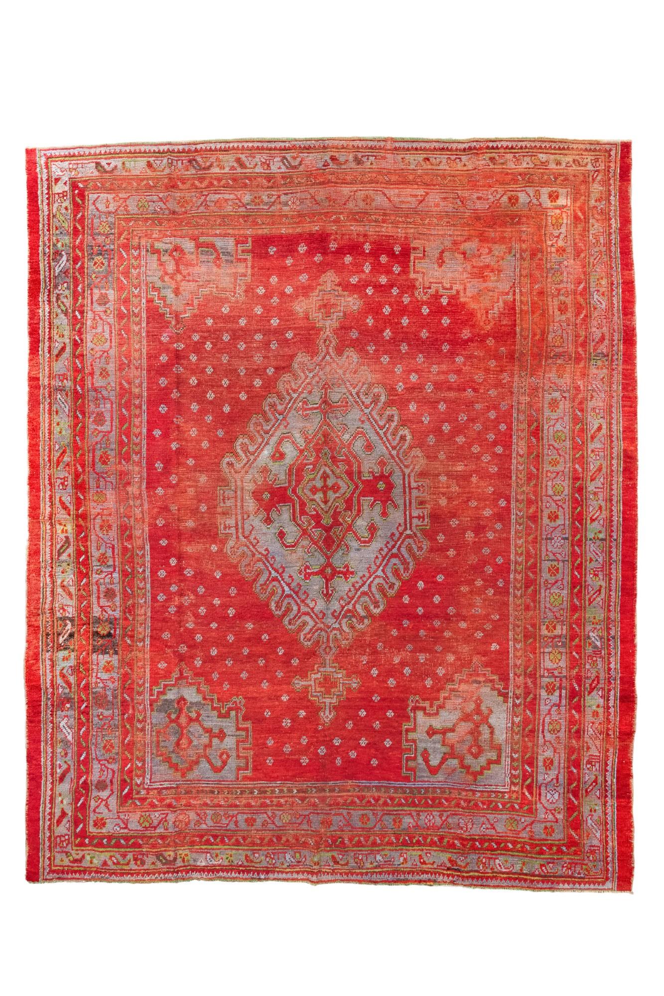 Questo antico tappeto turco Oushak, tessuto intorno al 1900, presenta un'imponente centro...
medaglione in grigio e avorio, su un campo rosso vibrante con un delicato Dot Dot Dot.
motivo. La tavolozza calda è ammorbidita da accenti di blu pastello,