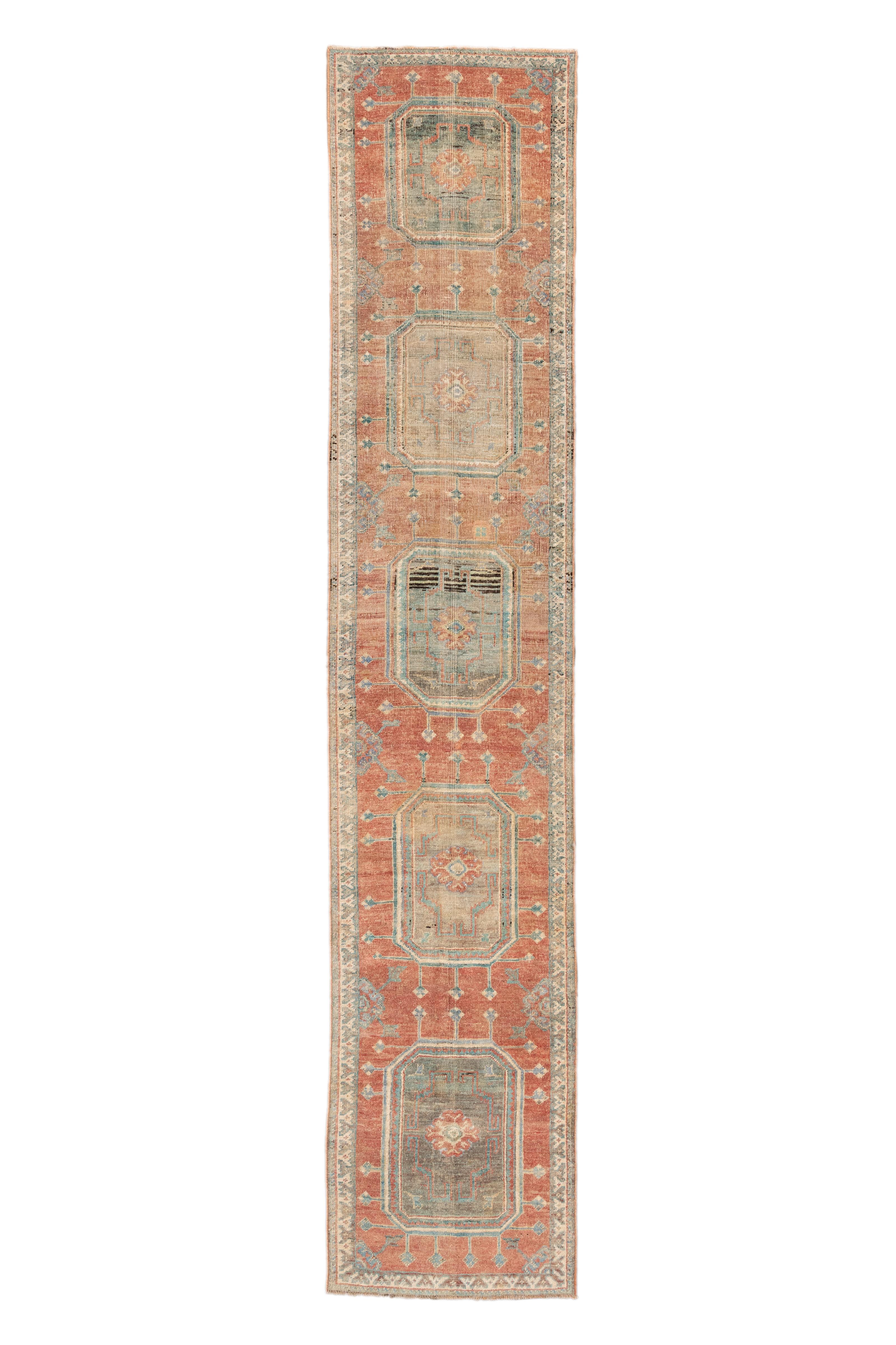  Un long et étroit chemin de table antique turc Oushak dans une combinaison harmonieuse de terre cuite, sarcelle pâle, ivoire doux et or discret. Le dessin présente une séquence de cinq grands médaillons octogonaux qui courent sur toute la longueur